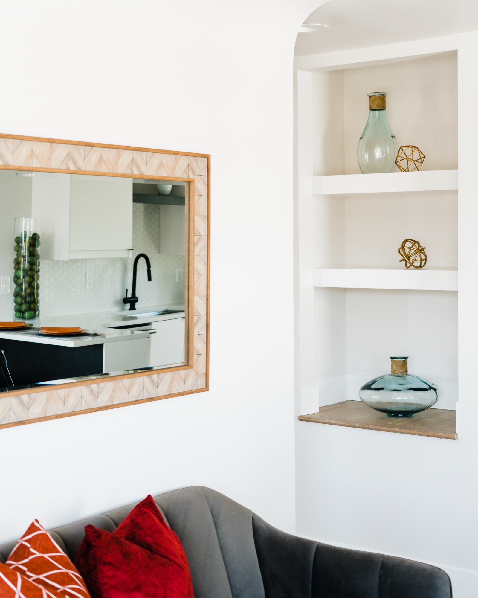 Built-in white niche shelves beside a framed mirror in the living room