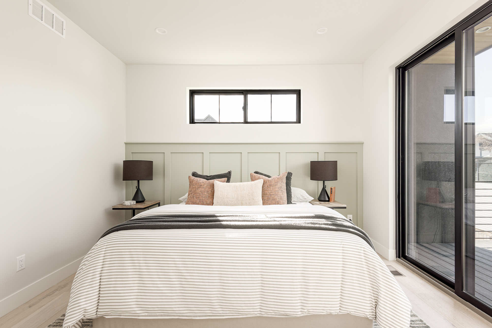 Primary bed straight on, with a paneled green wall and a narrow window above
