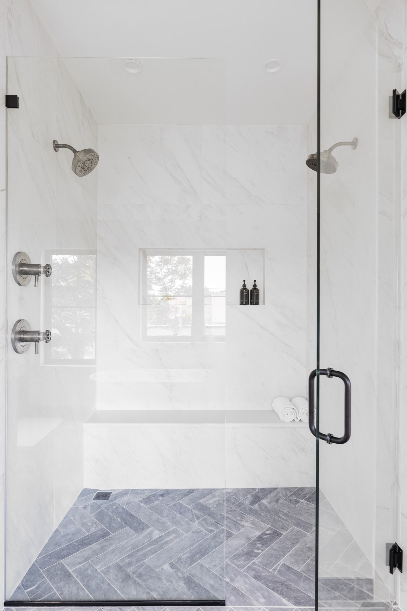 Freestanding white soaking tub with a floor-mounted faucet under a black-framed window