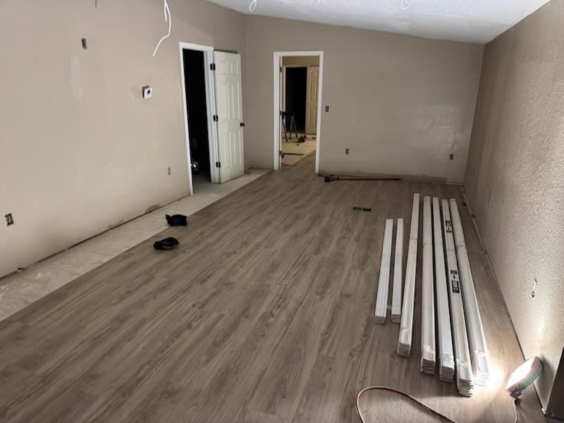 Open mobile home living area with grey brown luxury vinyl plank flooring and new trim