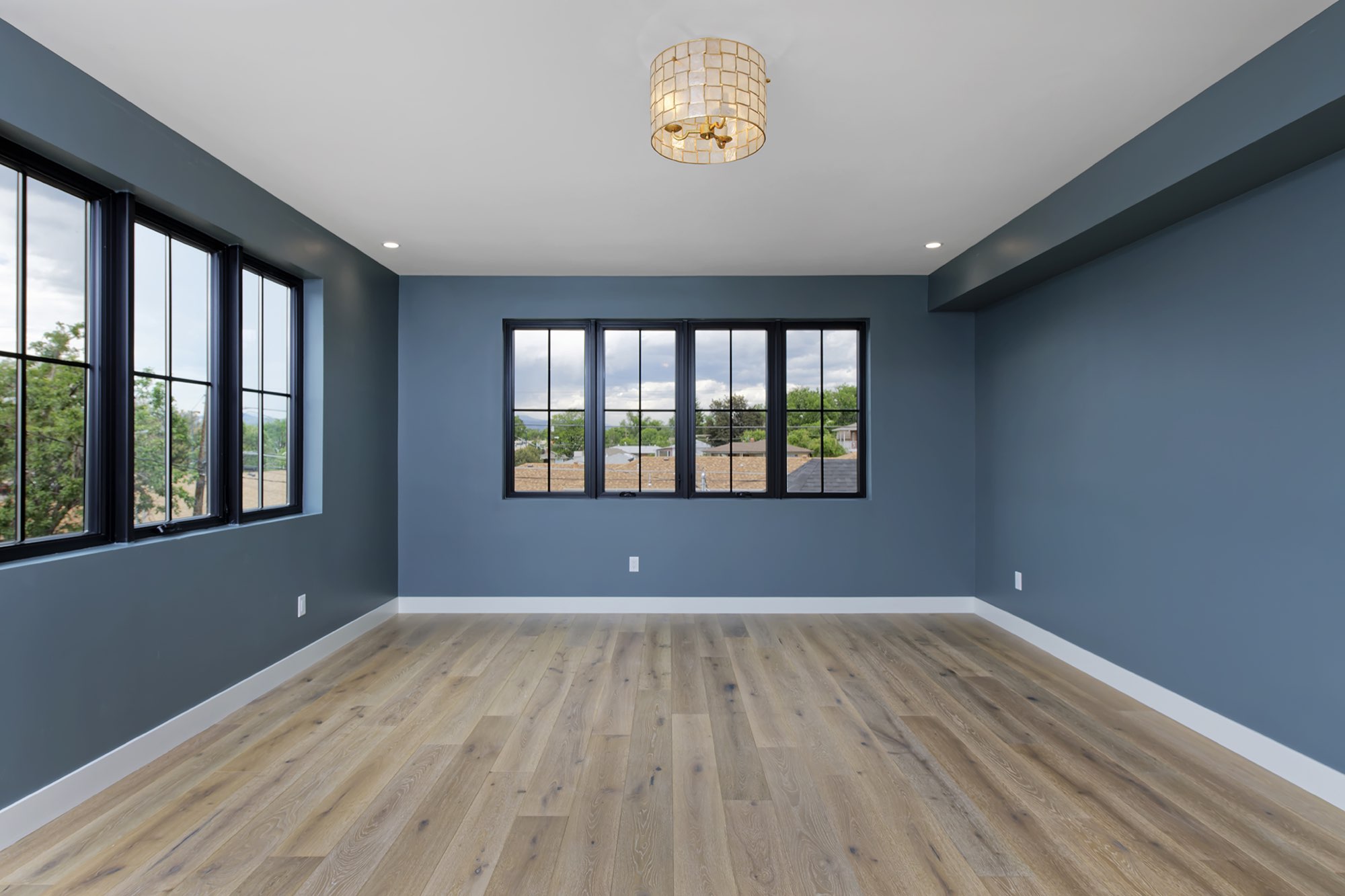 Slate blue bedroom with a shell-style light fixture and a row of black-framed windows