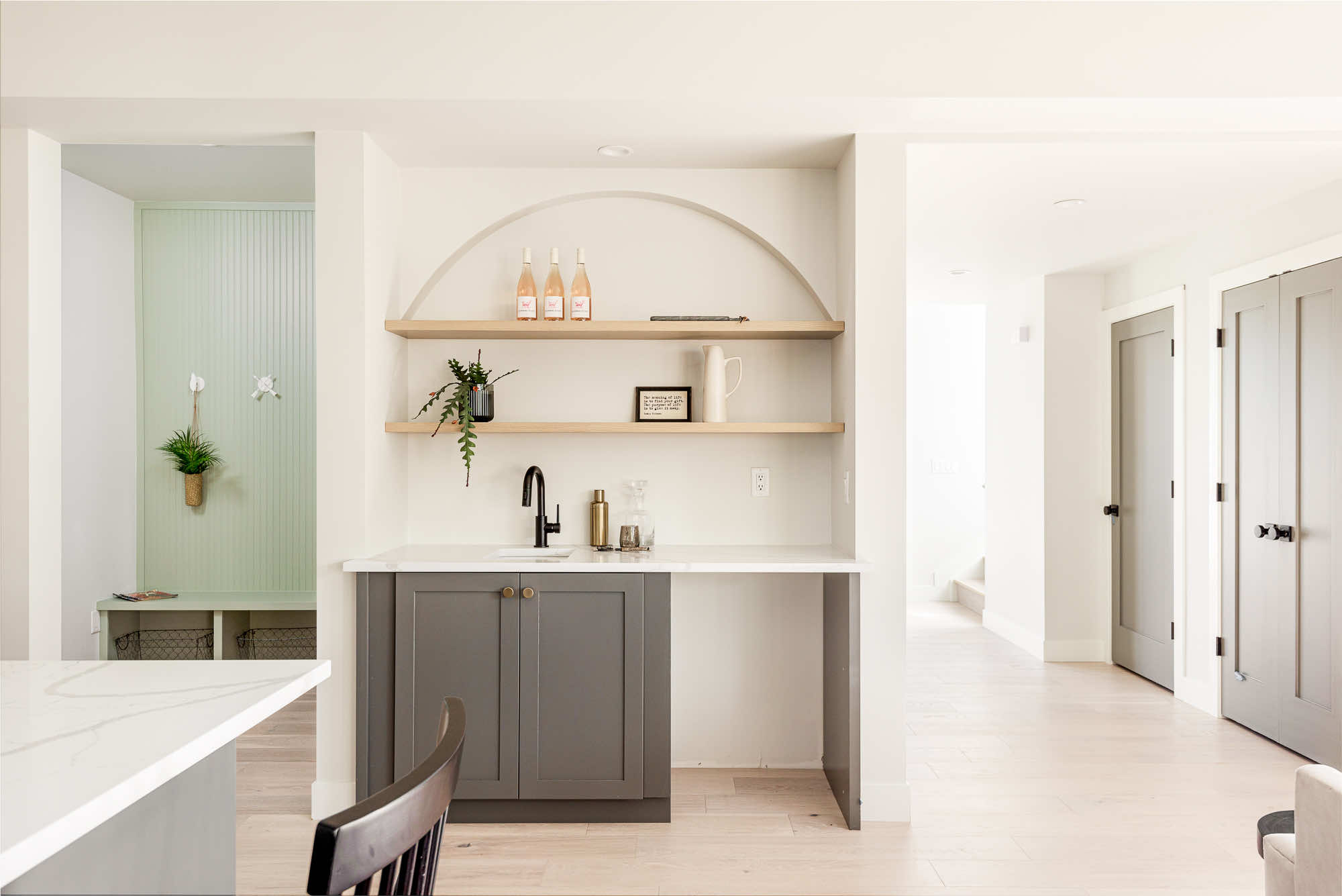 Arched wet bar niche with wood shelves and gray cabinets, with the green mudroom bench beside it