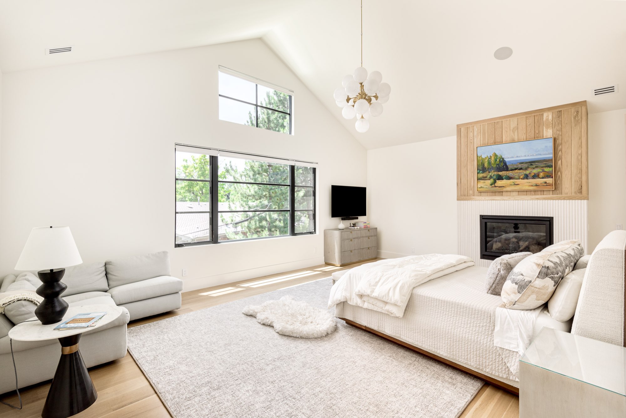 Bedroom with a sitting area, a fireplace and a vaulted ceiling with a cluster chandelier