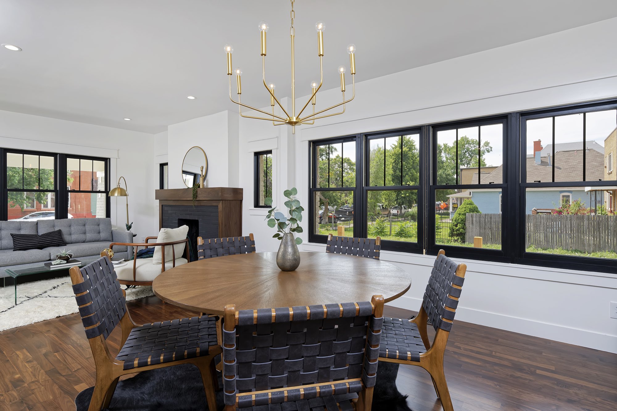 Dining area with a brass chandelier, black-framed windows and the fireplace in the background