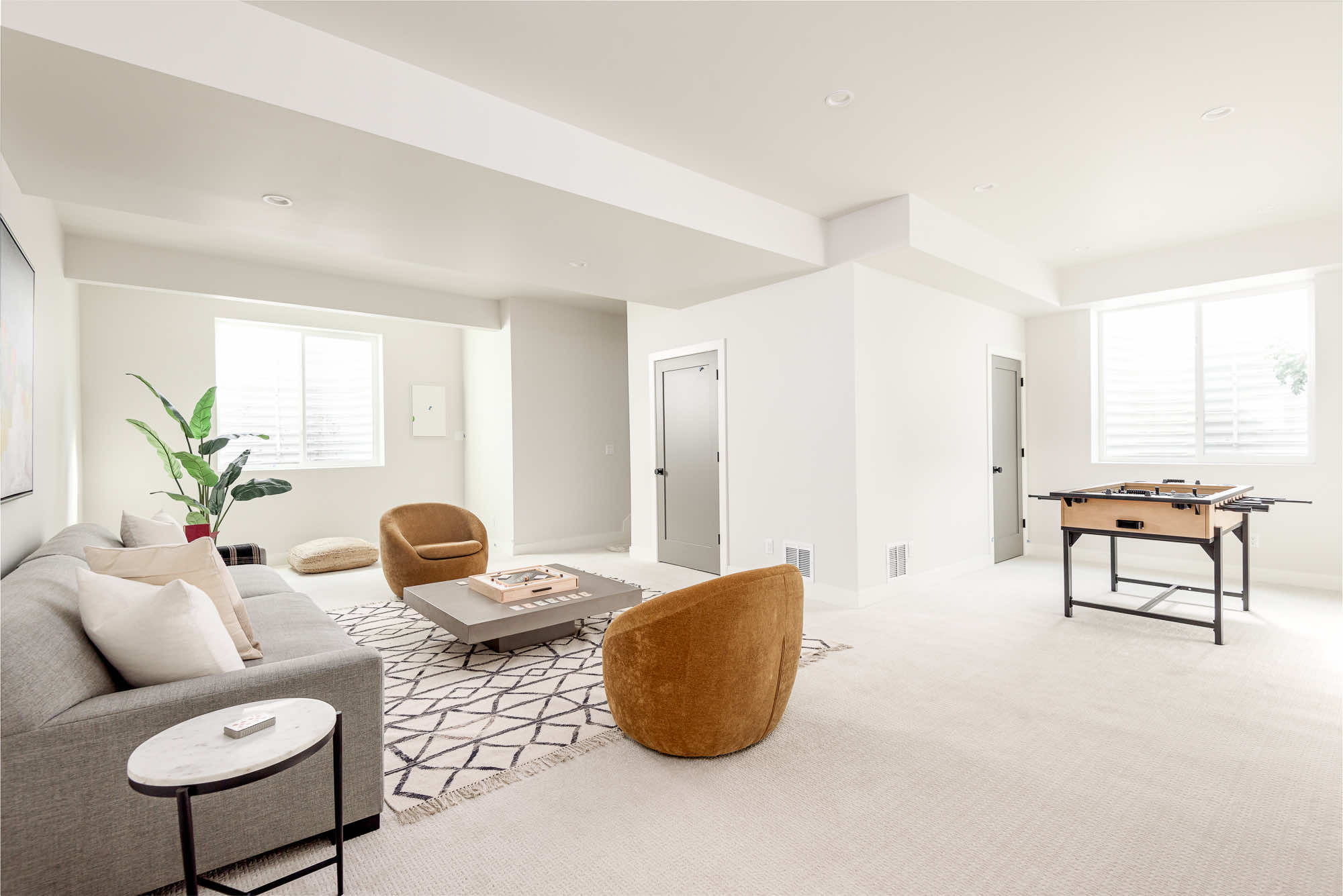 Lower-level family room looking down its length, with a long sofa and swivel chairs