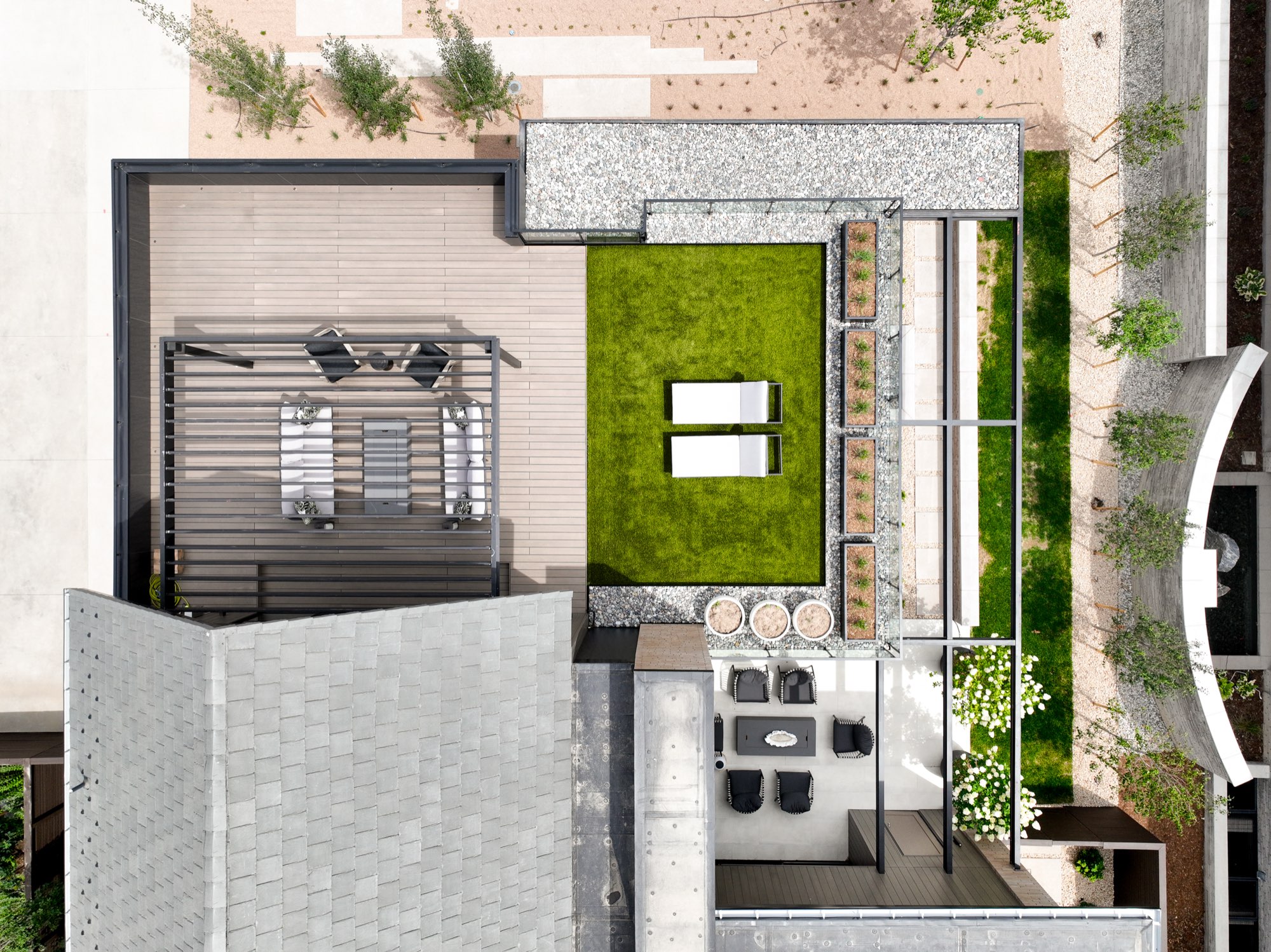 Overhead view of the terrace with green turf, loungers, a stone bar, a seating area and a fire table
