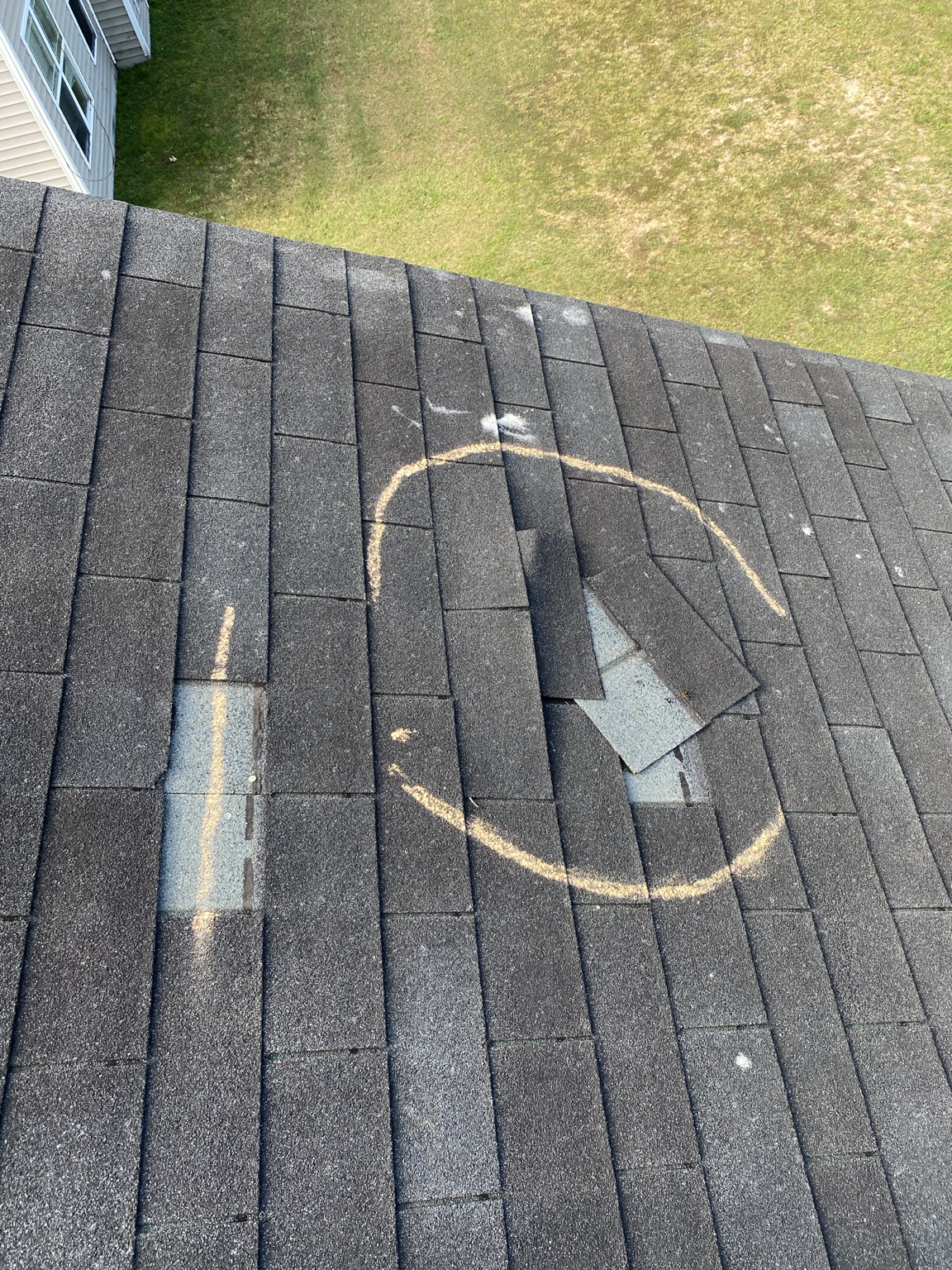 Lifted and creased shingles circled in chalk during a roof inspection