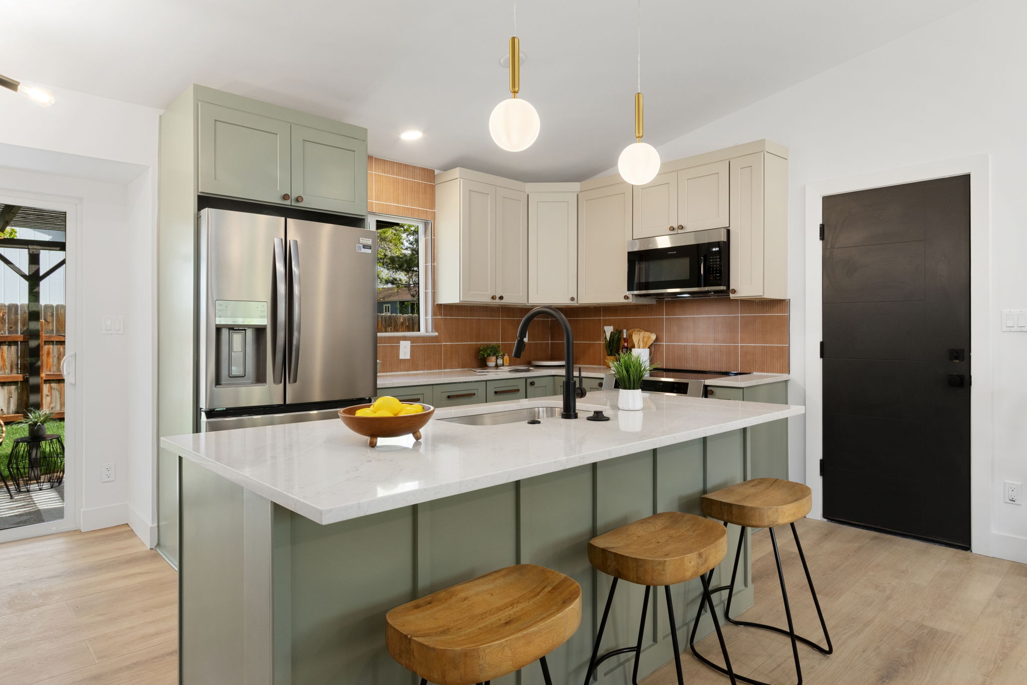 Kitchen island with bar stools, the refrigerator and a black interior door