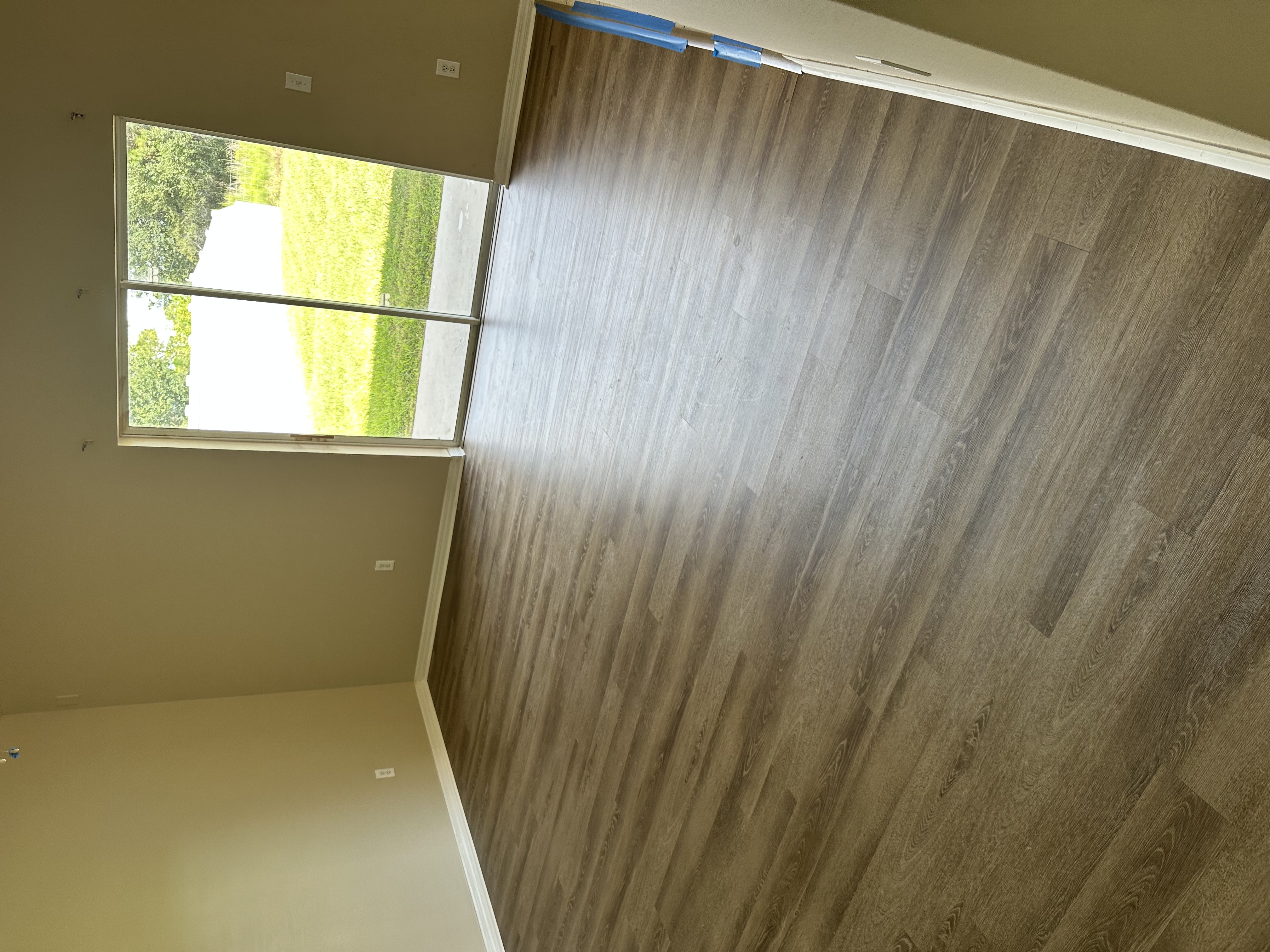 Empty Tampa, FL room with new dark plank flooring and a sliding door to the yard
