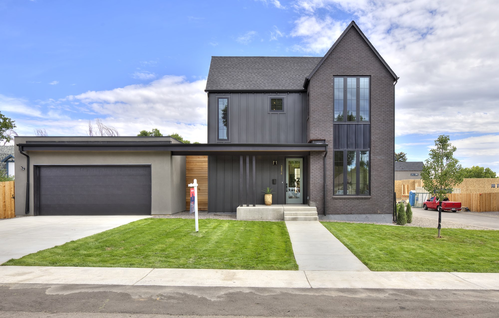 Front of 2874 Teller in Wheat Ridge, a modern farmhouse with a dark brick tower, charcoal board-and-batten siding, a covered entry and a garage wing