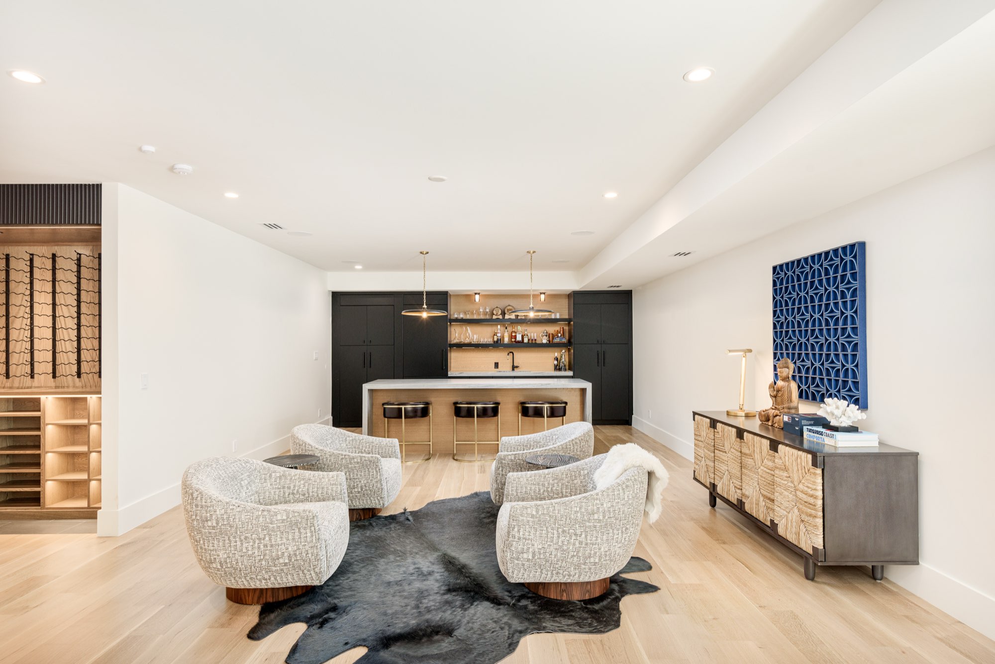 Lounge with swivel chairs in front of a dark bar, with a wine wall at the left