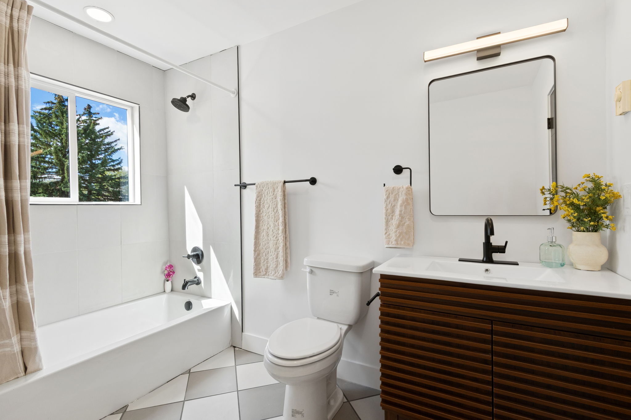 Hall bathroom with a tub, a slatted wood vanity and a checkerboard floor