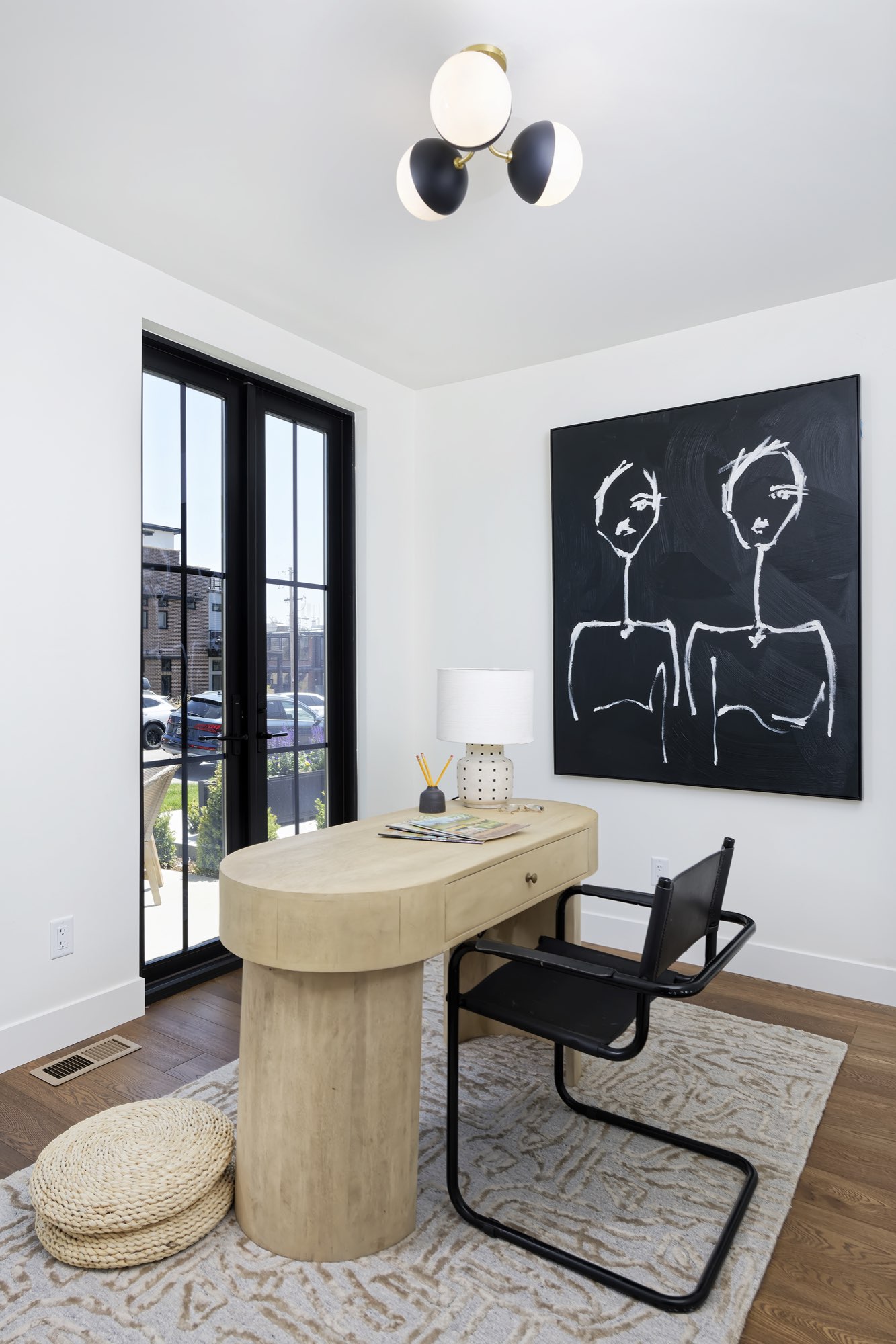 Corner of the room with black-framed French doors, wood floors and a desk with a black chair