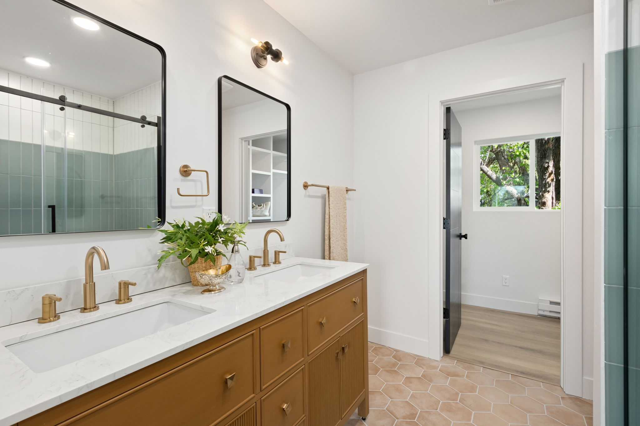 Primary bathroom with a double walnut-tone vanity, brass faucets and a terracotta hex tile floor