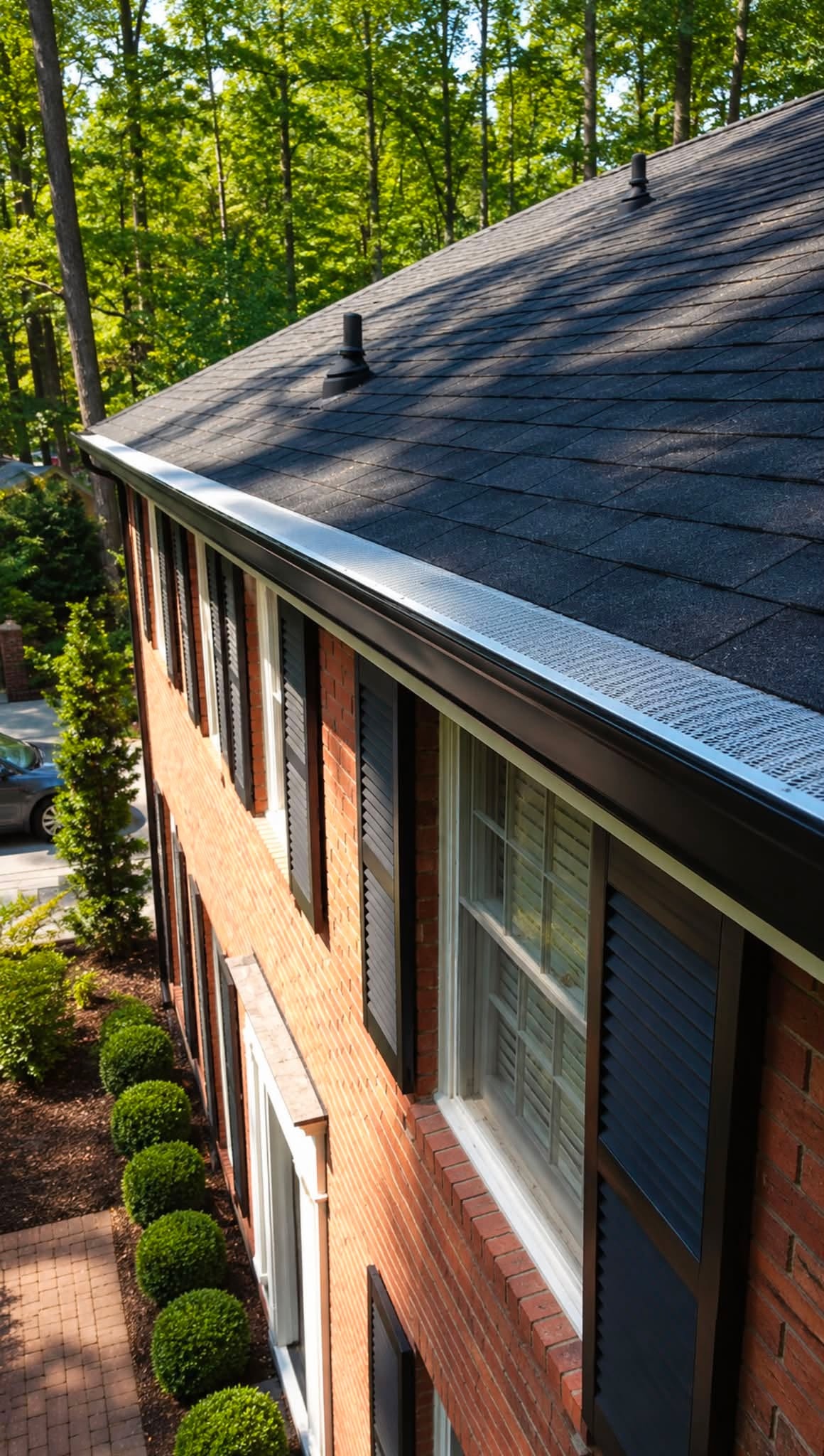 Finished gutter line with gutter guards along the roof edge of a brick home