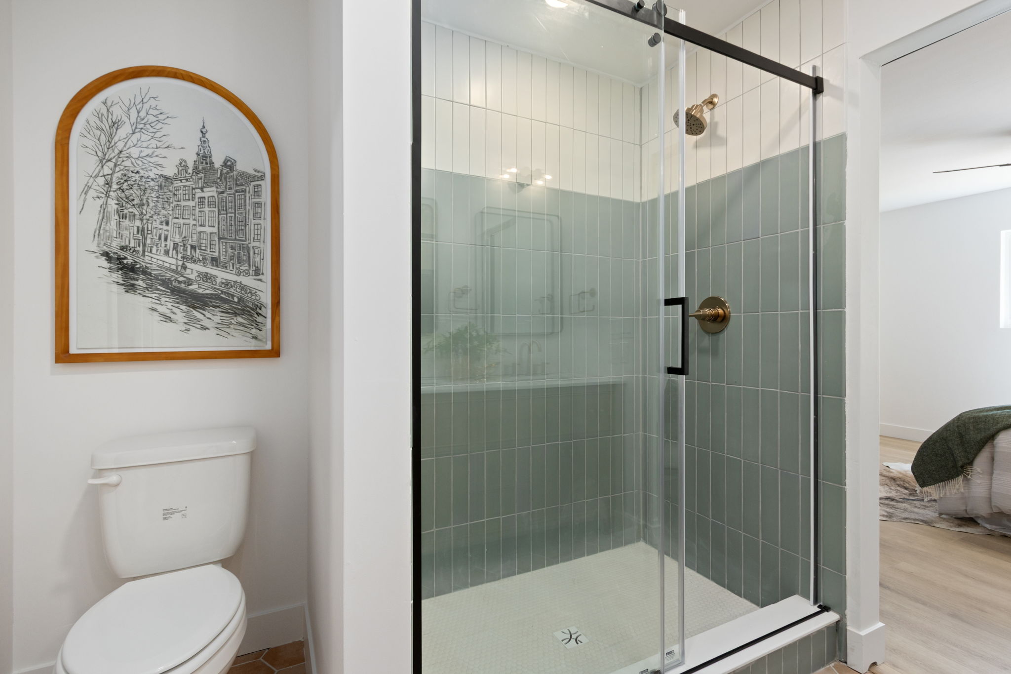 Primary bathroom glass shower finished in sage-green vertical tile
