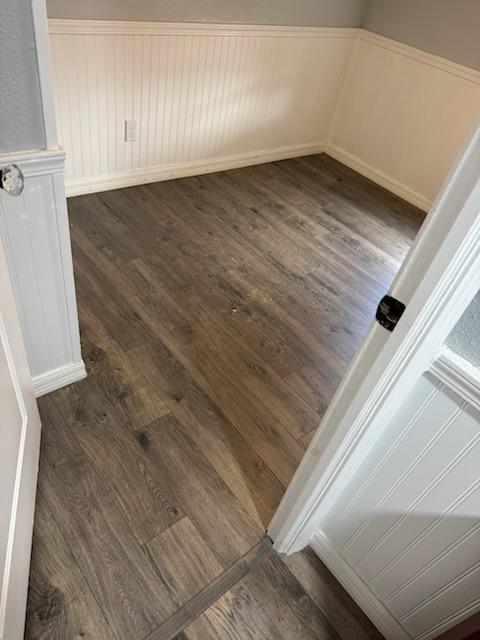 Dark wood-look luxury vinyl plank flooring installed in a mobile home room with white beadboard wainscot