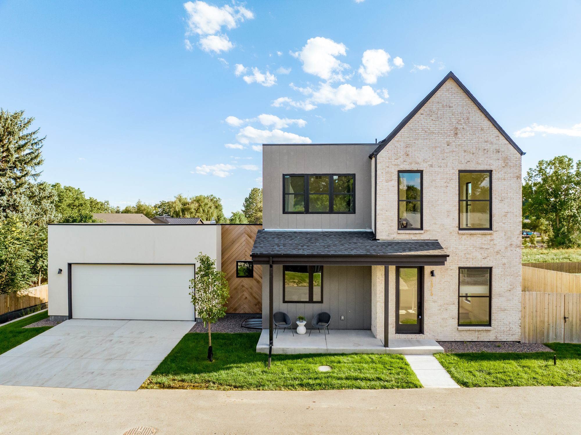 Front of the new custom home in Wheat Ridge with a tall whitewashed brick gable, covered porch and attached two-car garage