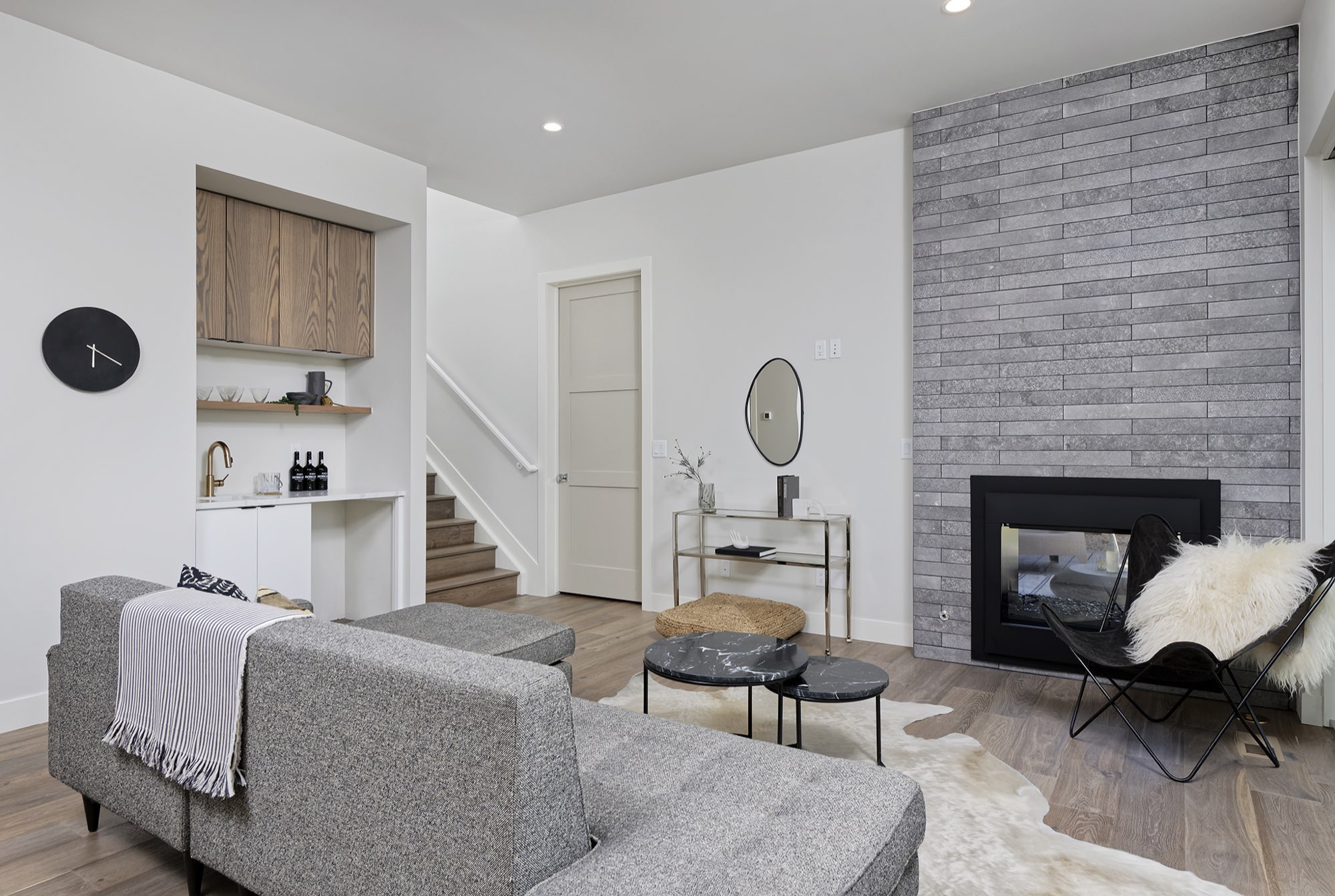 Living room toward the wet bar niche and the stair, with the gray stacked fireplace wall at right
