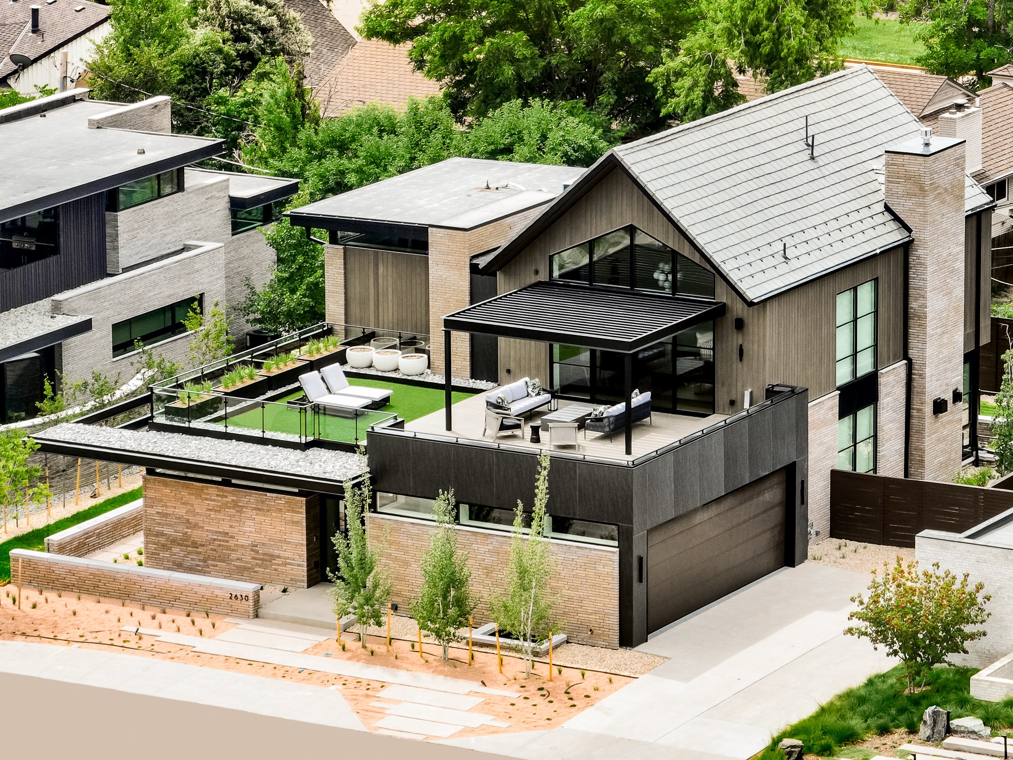 Aerial view of the Denver custom home showing the gabled front, dark siding, roof terrace and garage