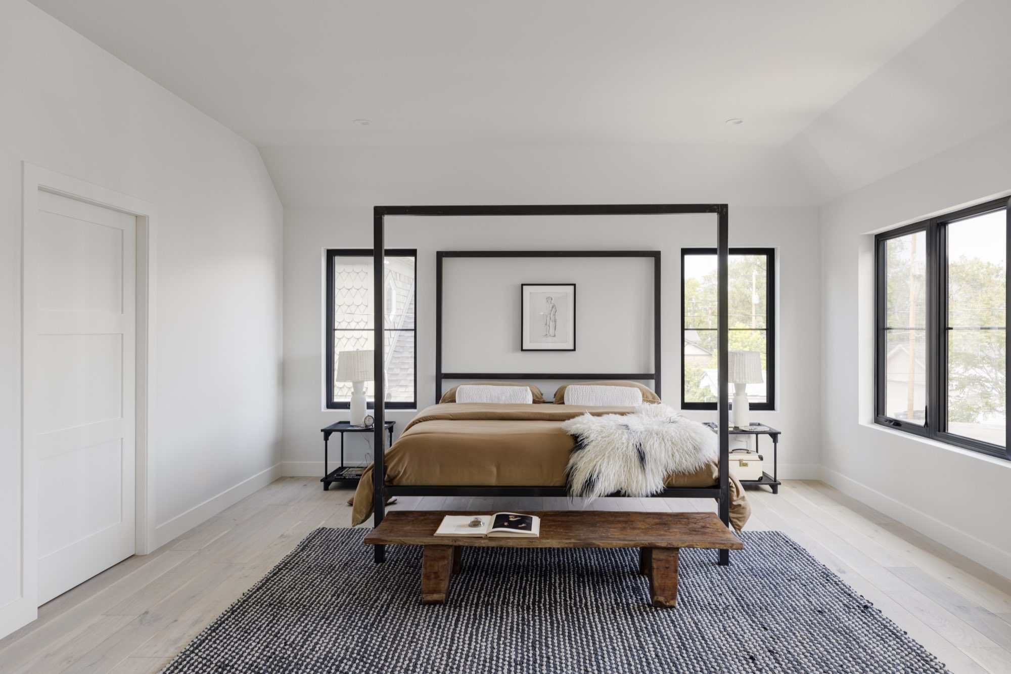 Upstairs bedroom with black-framed windows, light wood floors and a sloped white ceiling
