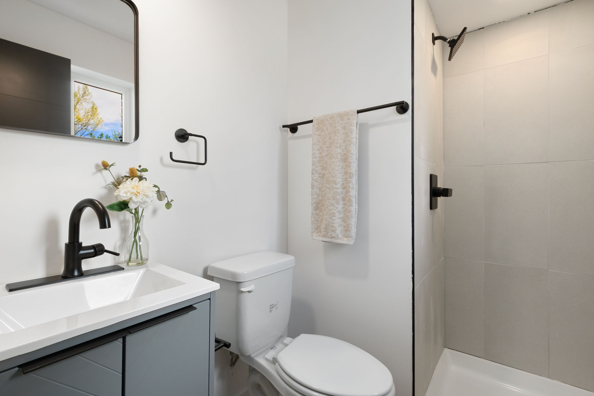 Third bathroom with a gray vanity and a tiled shower
