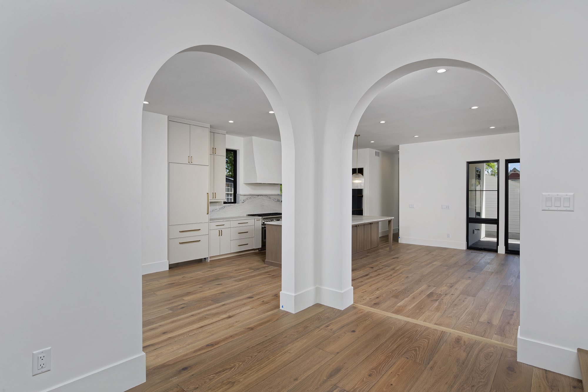 Two arched openings from the entry looking into the kitchen and the open main level