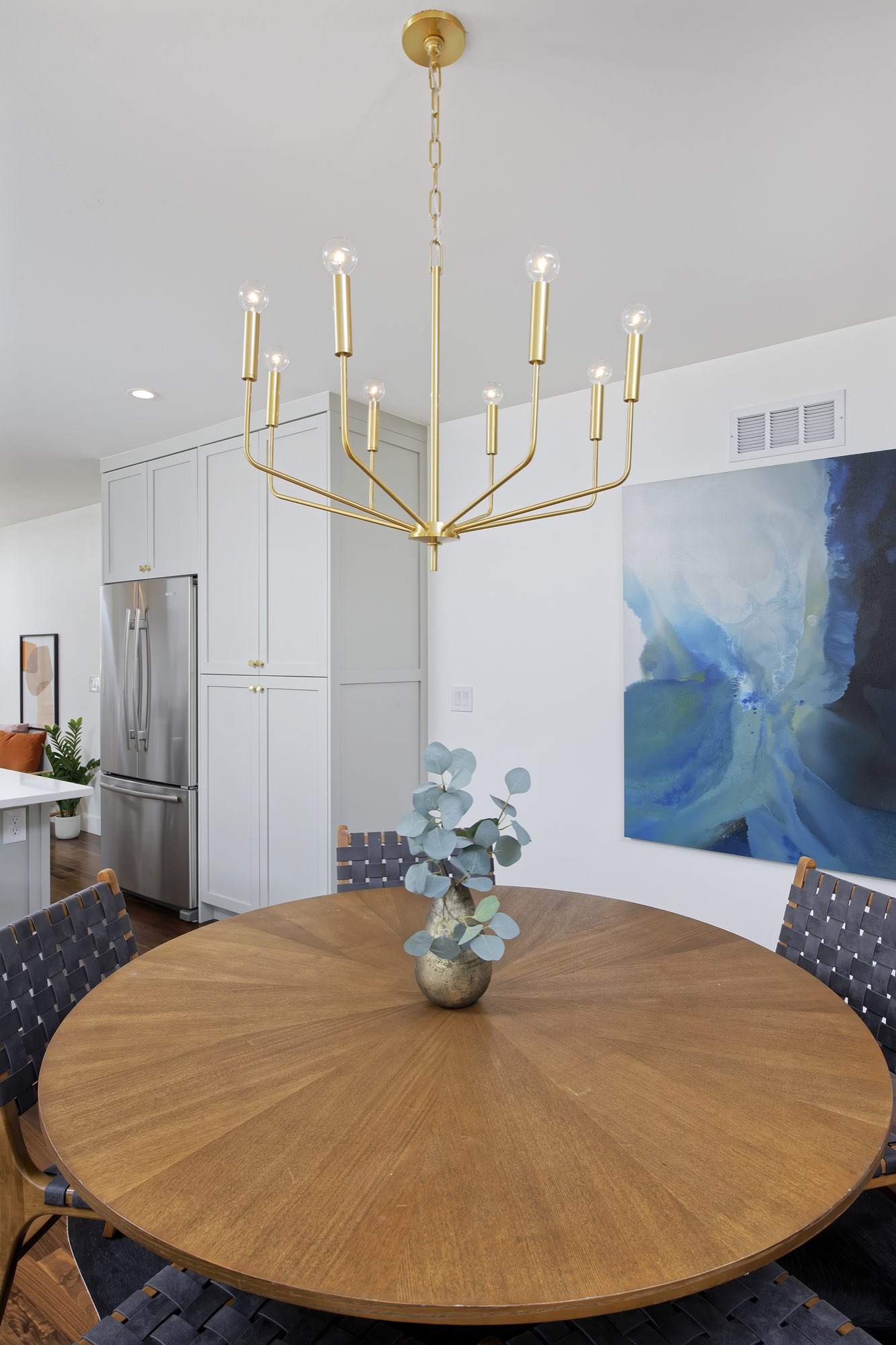 Round dining table under a brass candle-style chandelier beside the kitchen