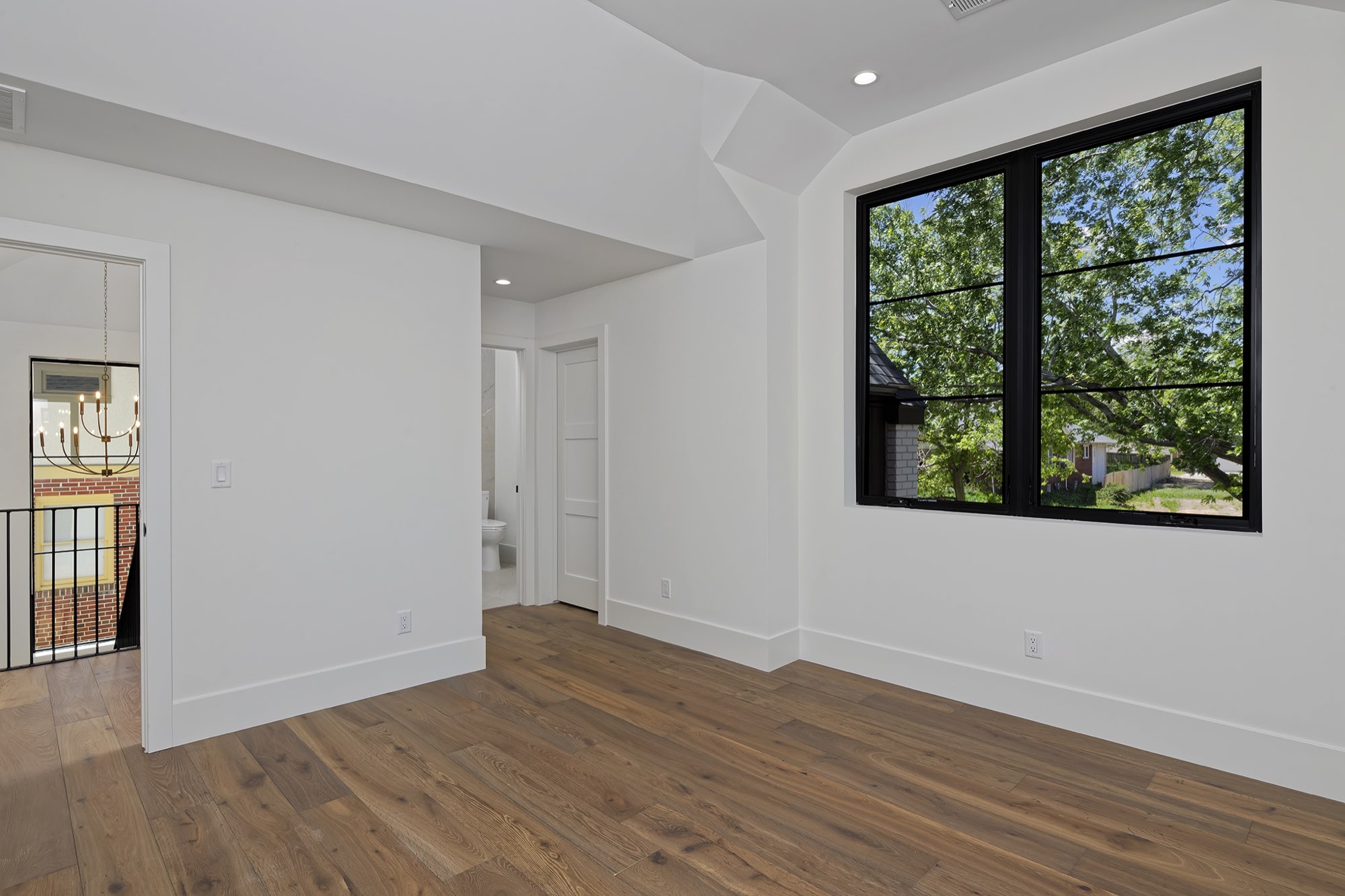 Upstairs room with wood floors, black-framed windows and a view of the tree tops