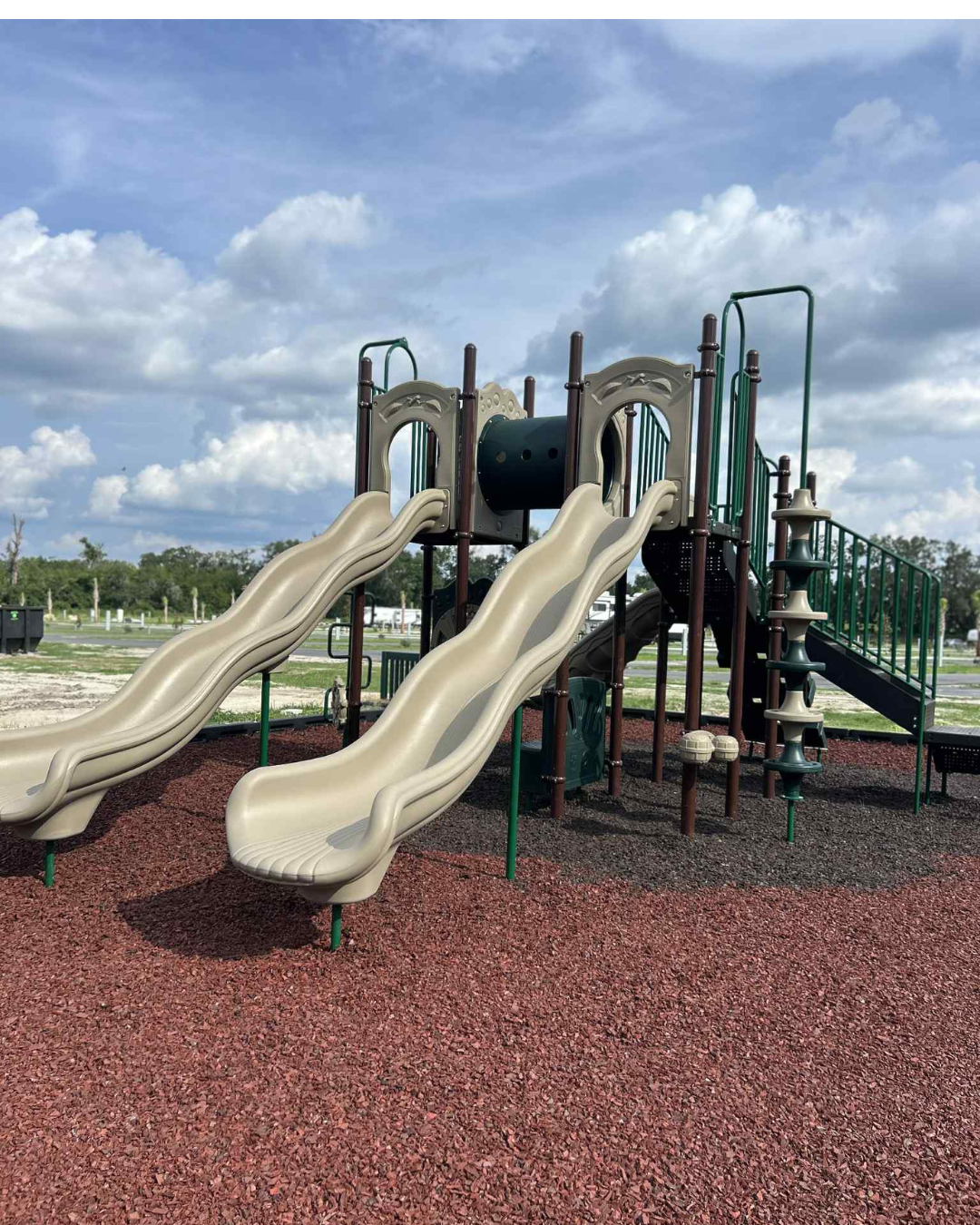 The playground at Heritage Oaks RV Resort, with double slides and a climbing structure on a rubber mulch surface