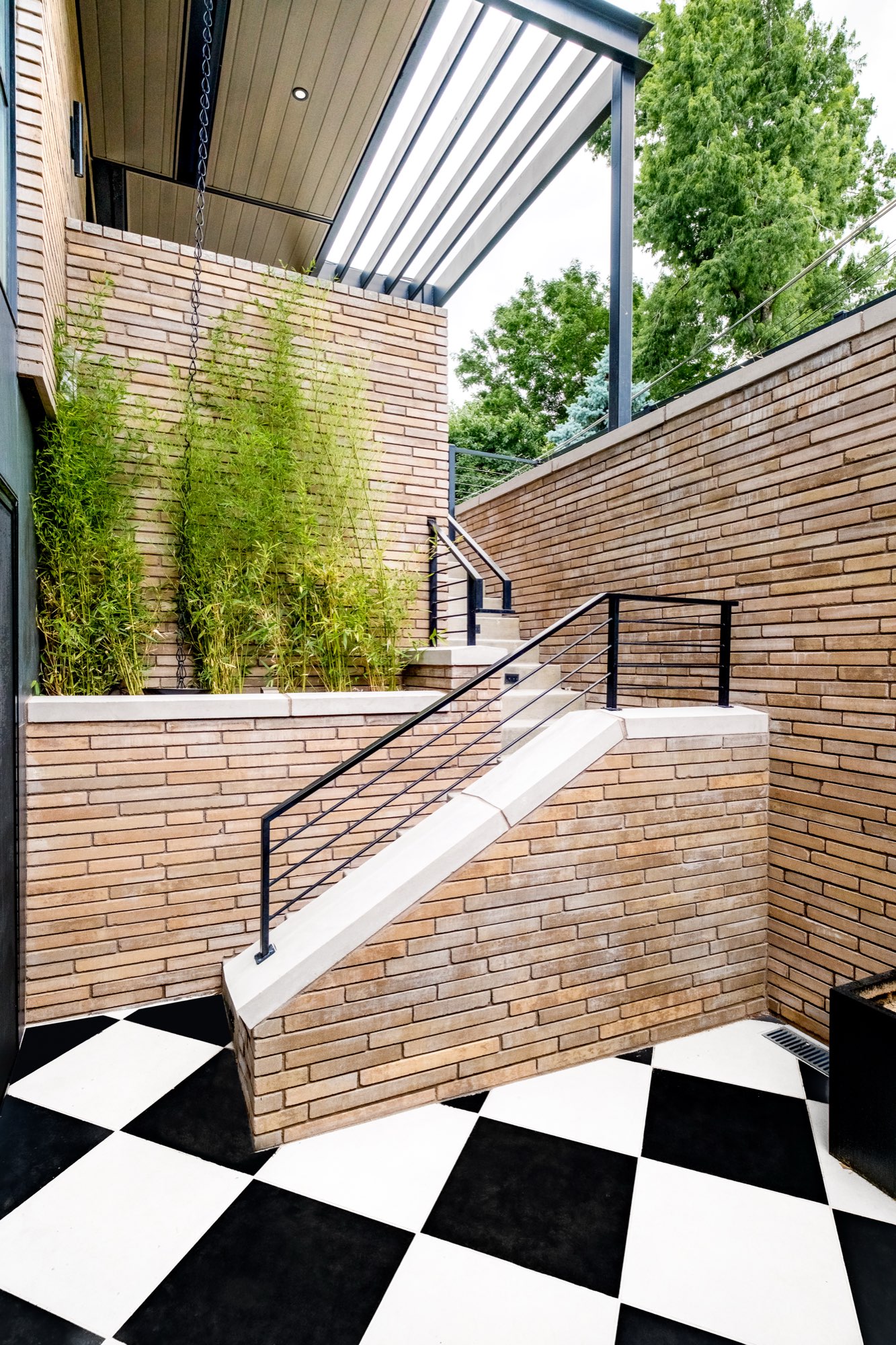 Tan brick stair with a black metal railing beside a black and white checkerboard court