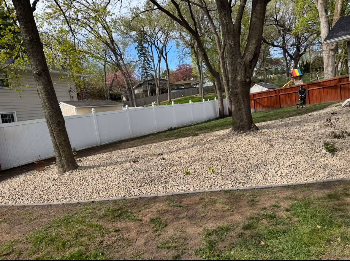 River Rock and Paver Edging Around a Backyard Tree Line