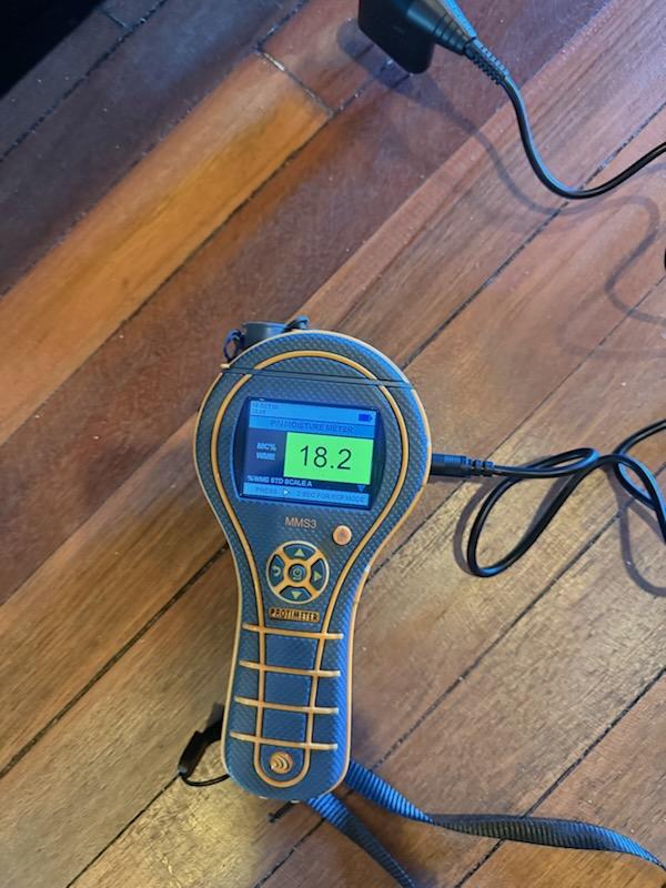 Moisture meter taking a reading on a hardwood floor