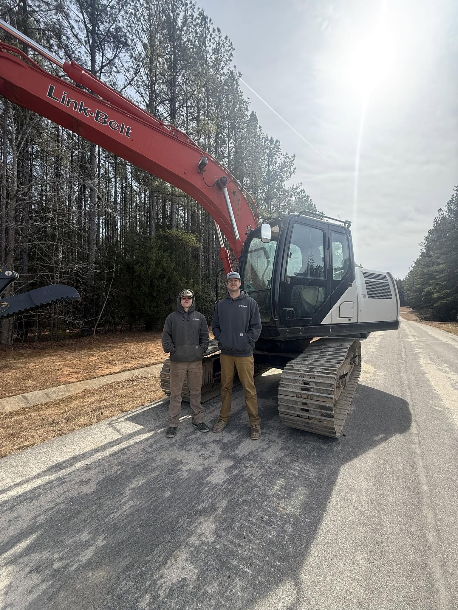 Capece Land Solutions crew standing beside a Link-Belt excavator on a cleared site in Mechanicsville, Virginia