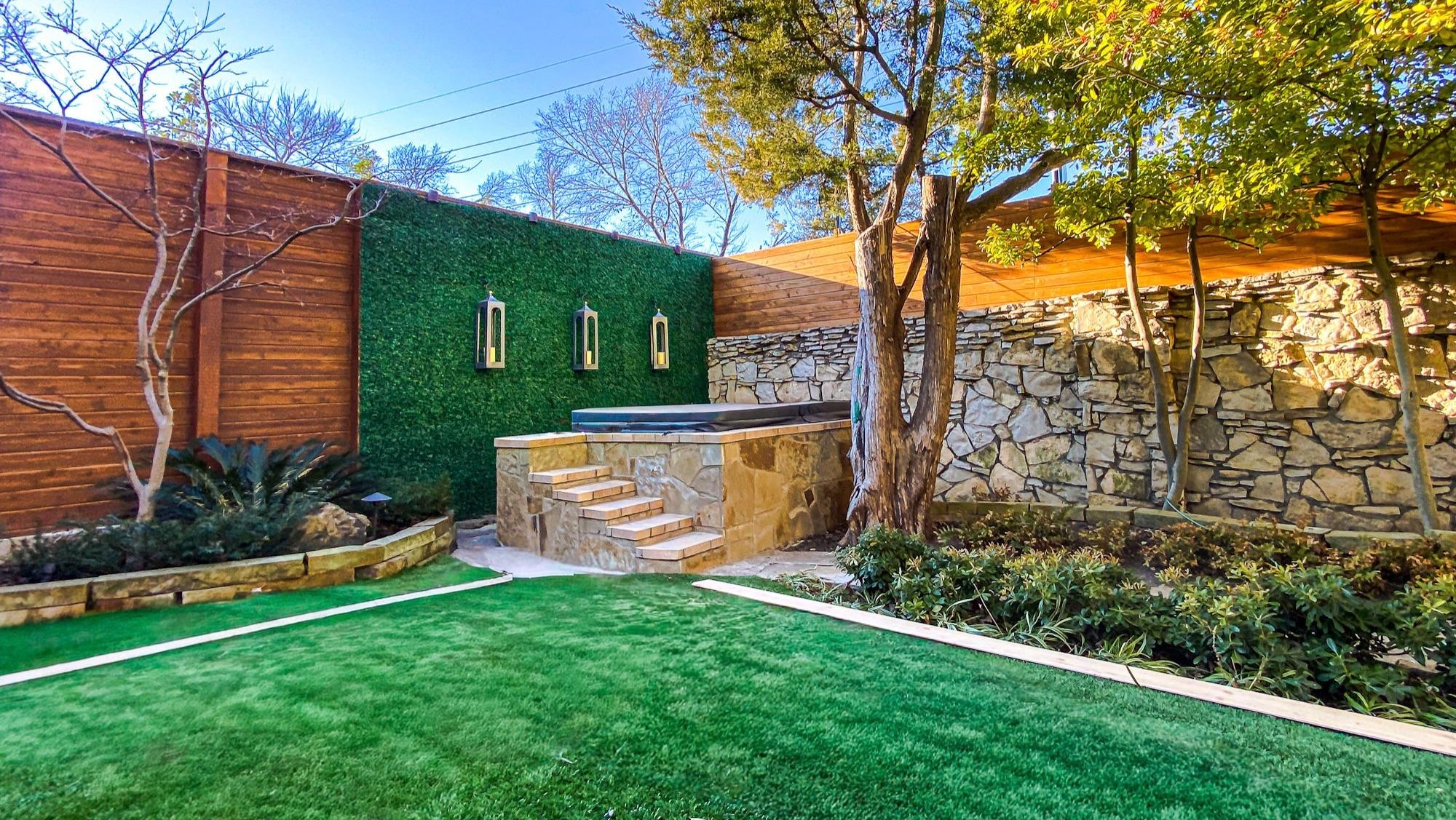 Artificial turf lawn with stone retaining wall and hot tub