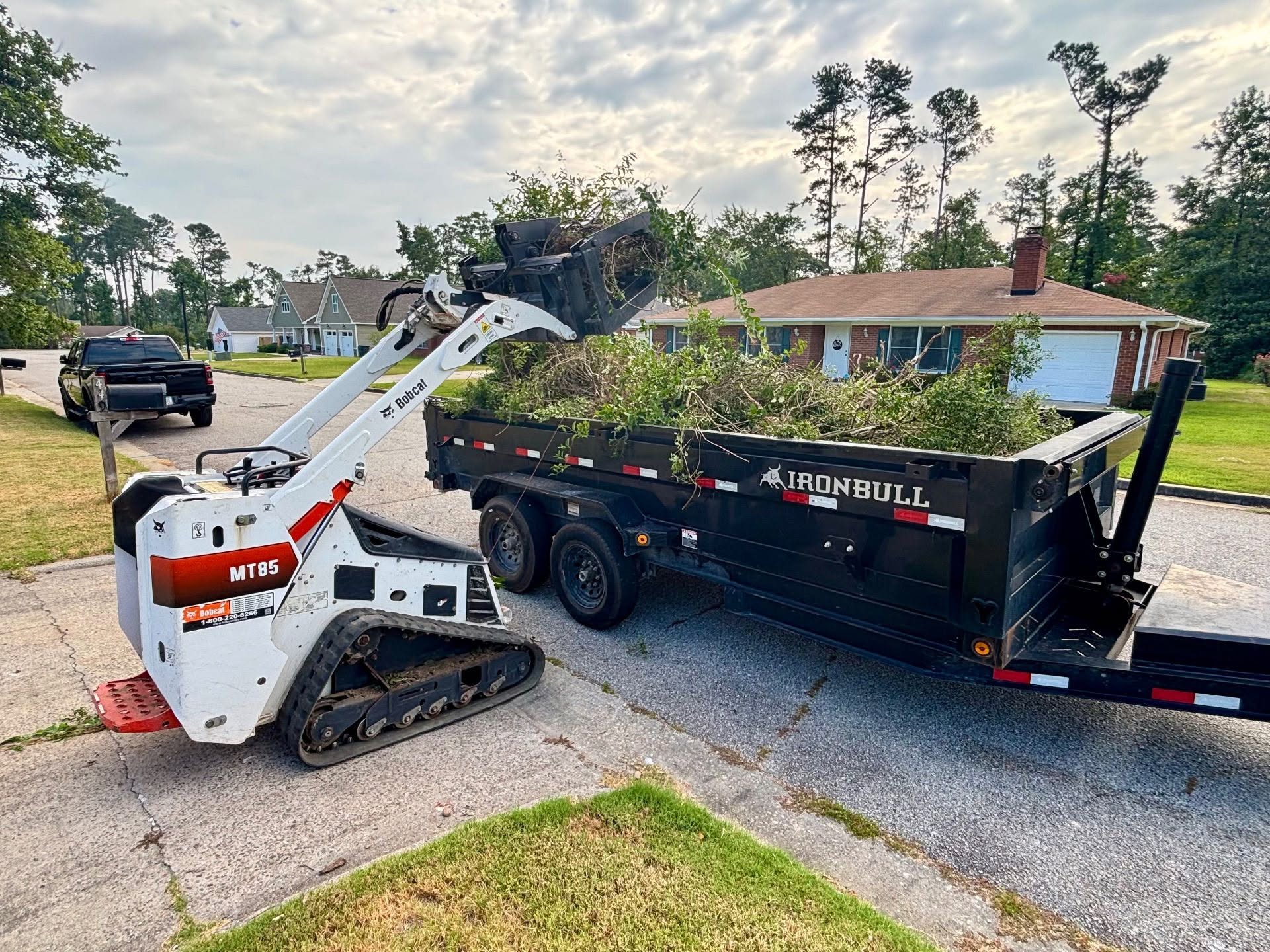 Skid steer loading brush and debris into a dump trailer