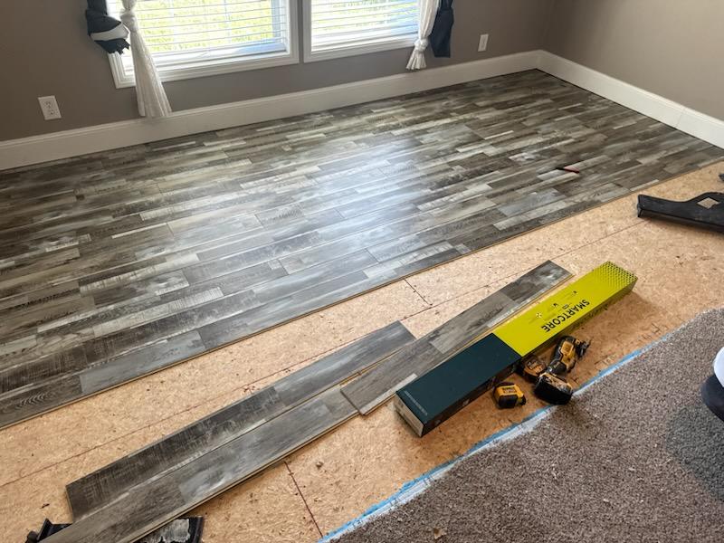 Weathered grey plank flooring part way through installation with fresh boards and underlayment visible