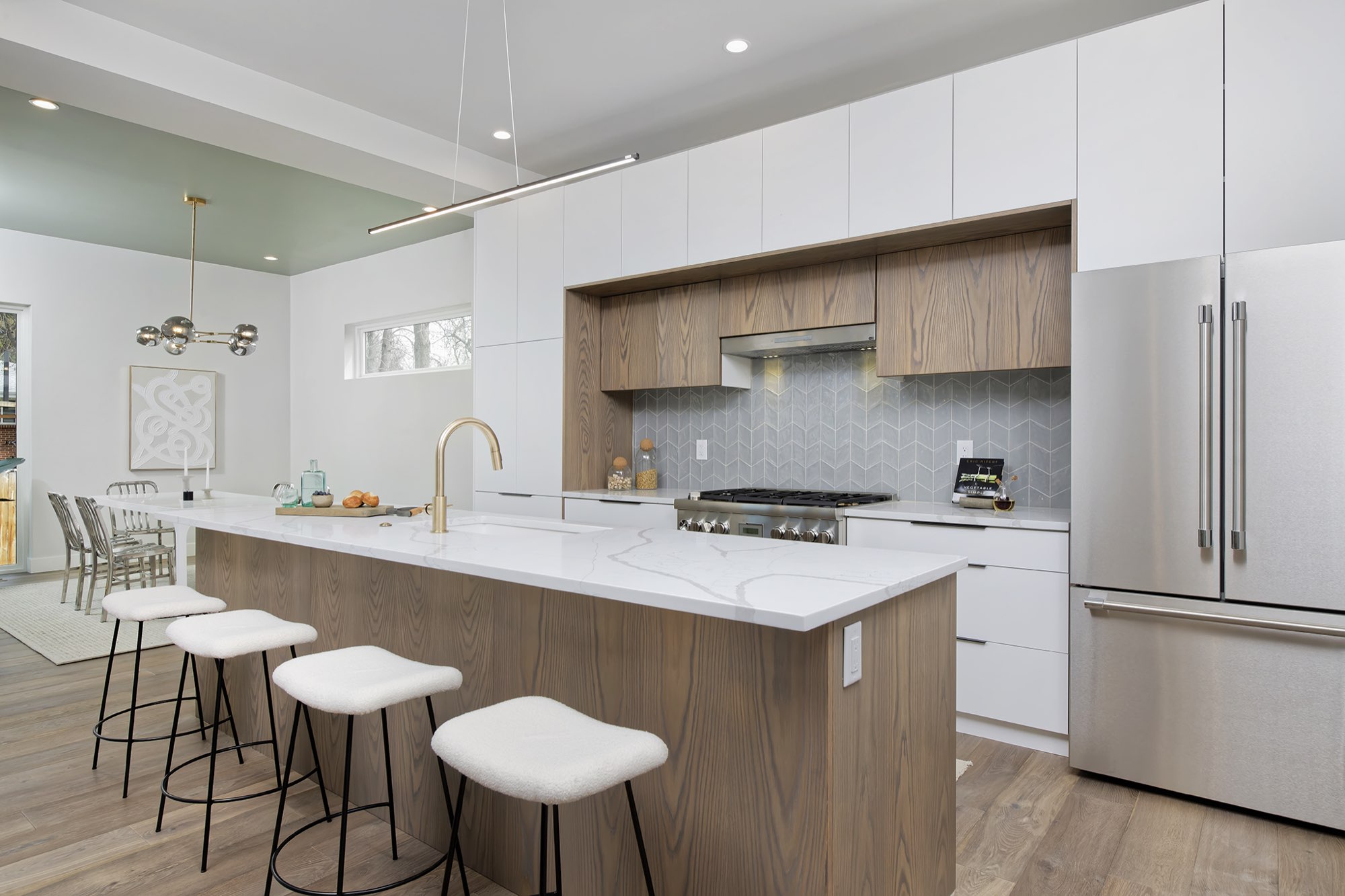 Kitchen with a sage green ceiling and the dining room visible past the island, stainless refrigerator at right
