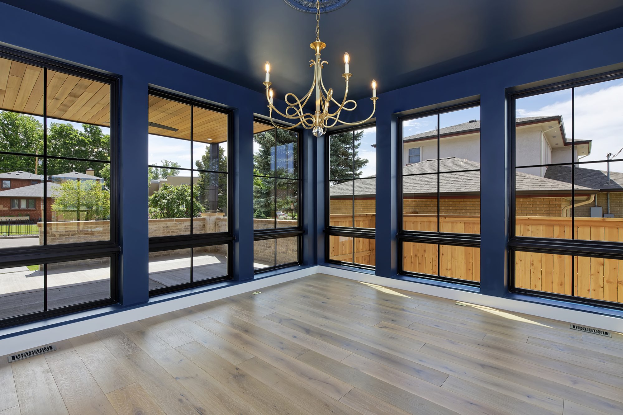 Dining room with a brass chandelier and wall sconce, with an opening through to the fireplace