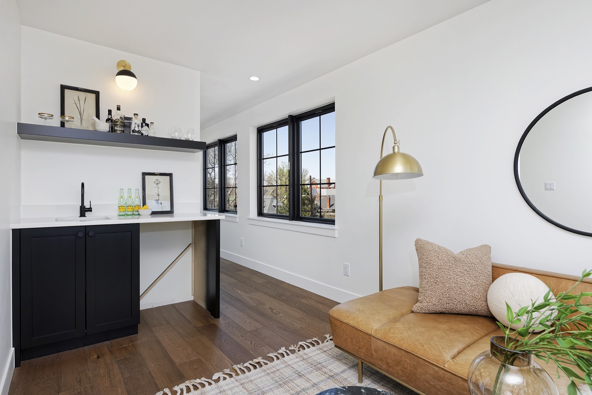 Lounge corner with a bar of dark cabinets, a floating shelf and a black-framed window