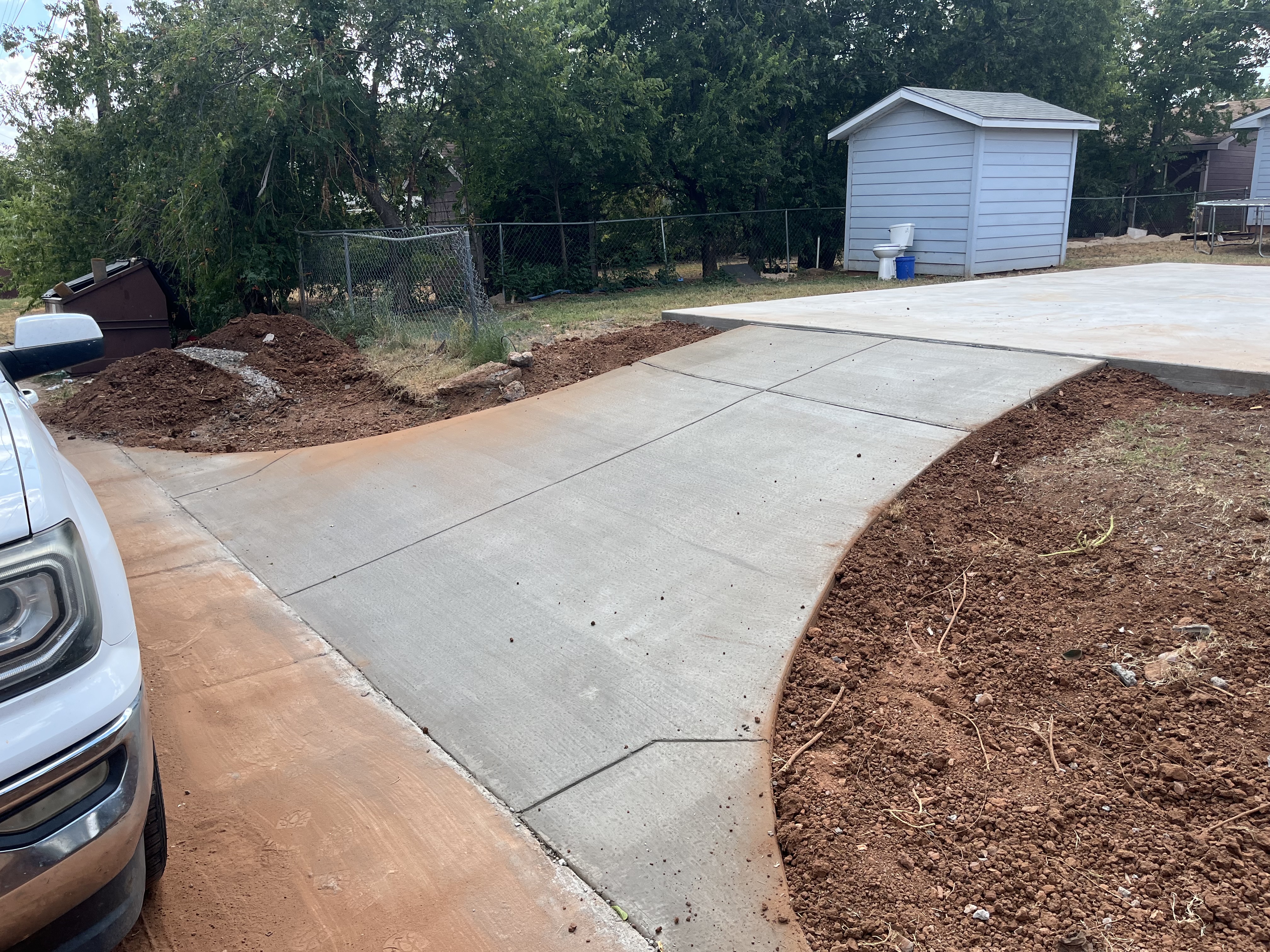 Curved concrete driveway extension poured beside a garage by Rock of Ages Concrete LLC