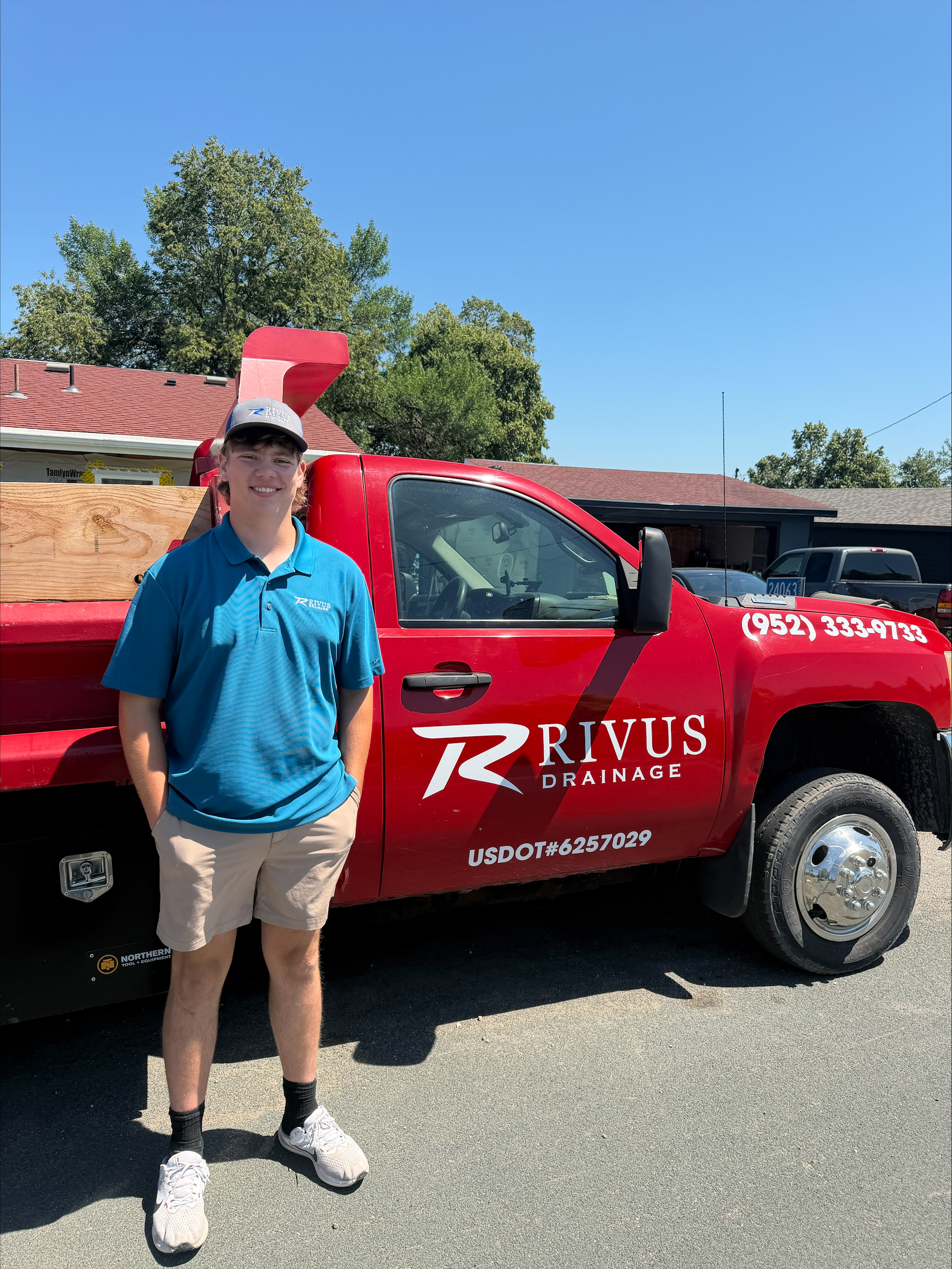 Isaiah Church, owner of Rivus Drainage, standing in front of the branded Rivus Drainage truck