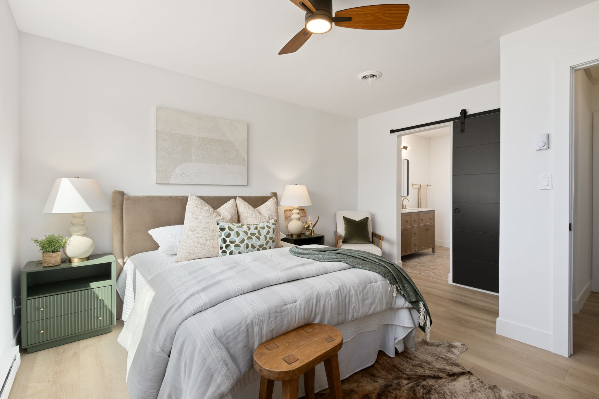 Staged primary bedroom with the black sliding barn door visible beyond