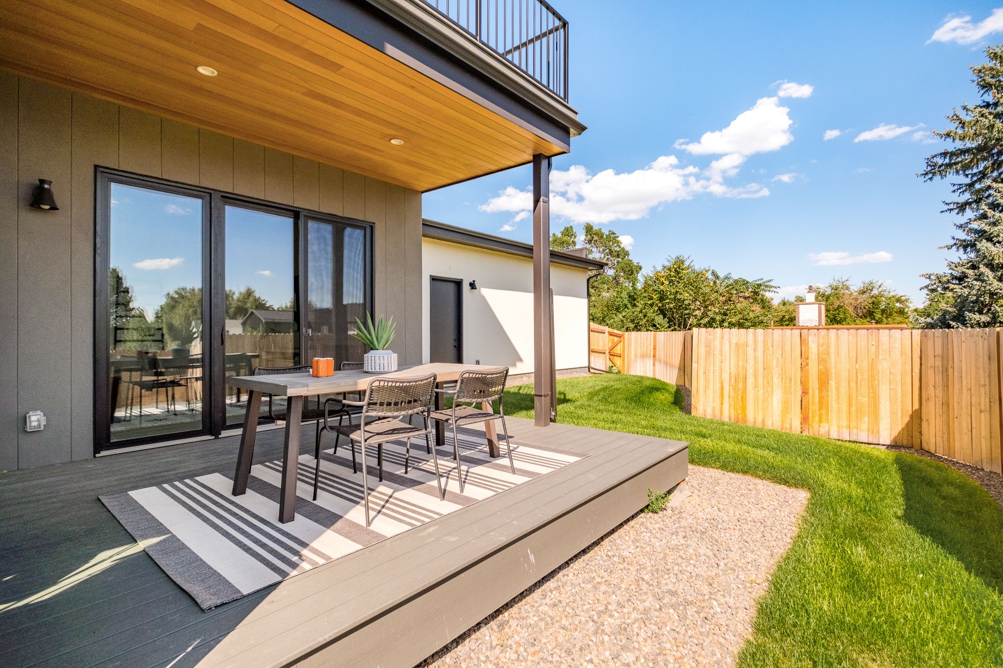Back deck dining area under a wood soffit at the Wheat Ridge home, with the lawn beyond