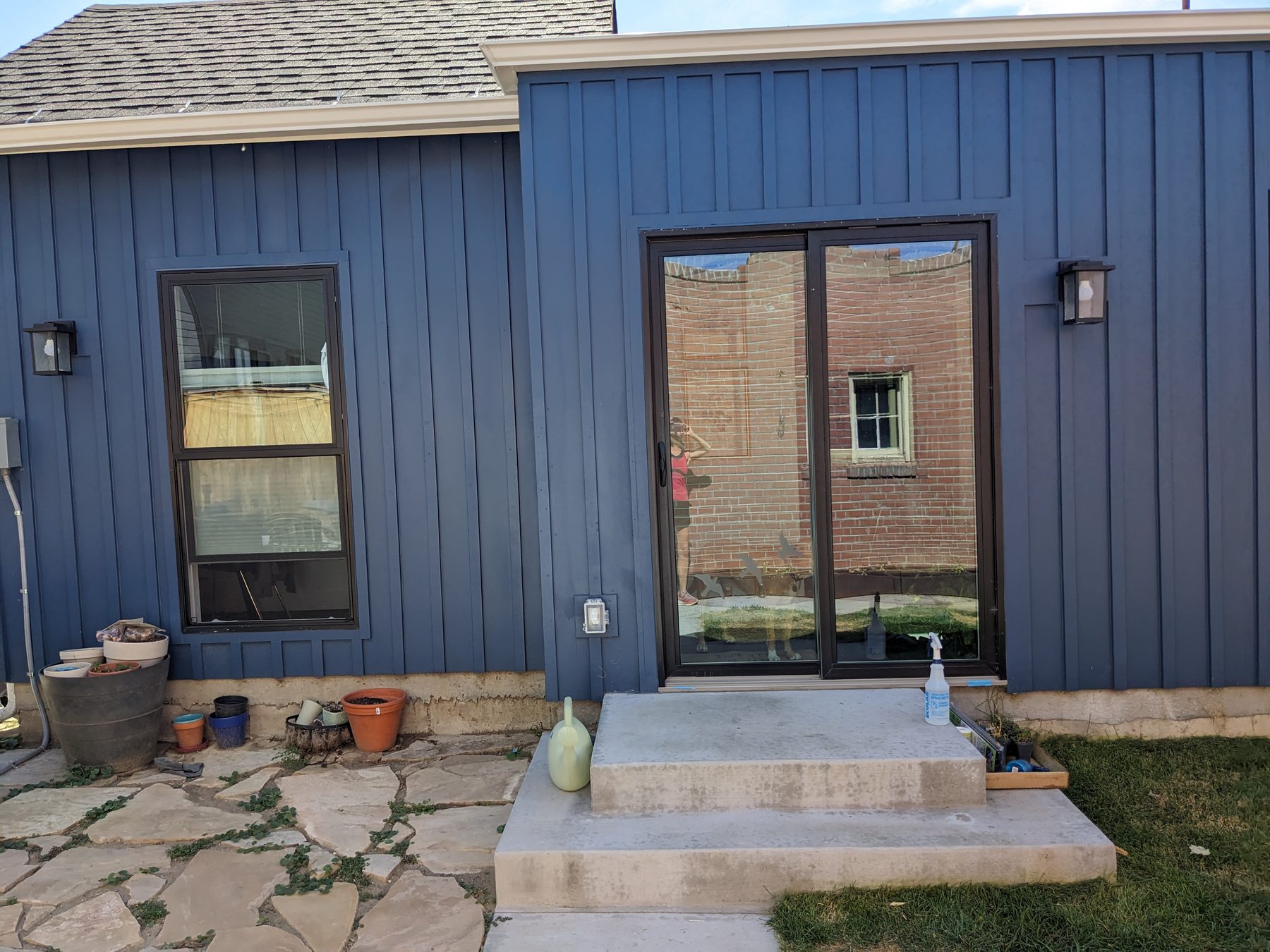 Home addition with blue board-and-batten siding, a sliding patio door and new concrete steps