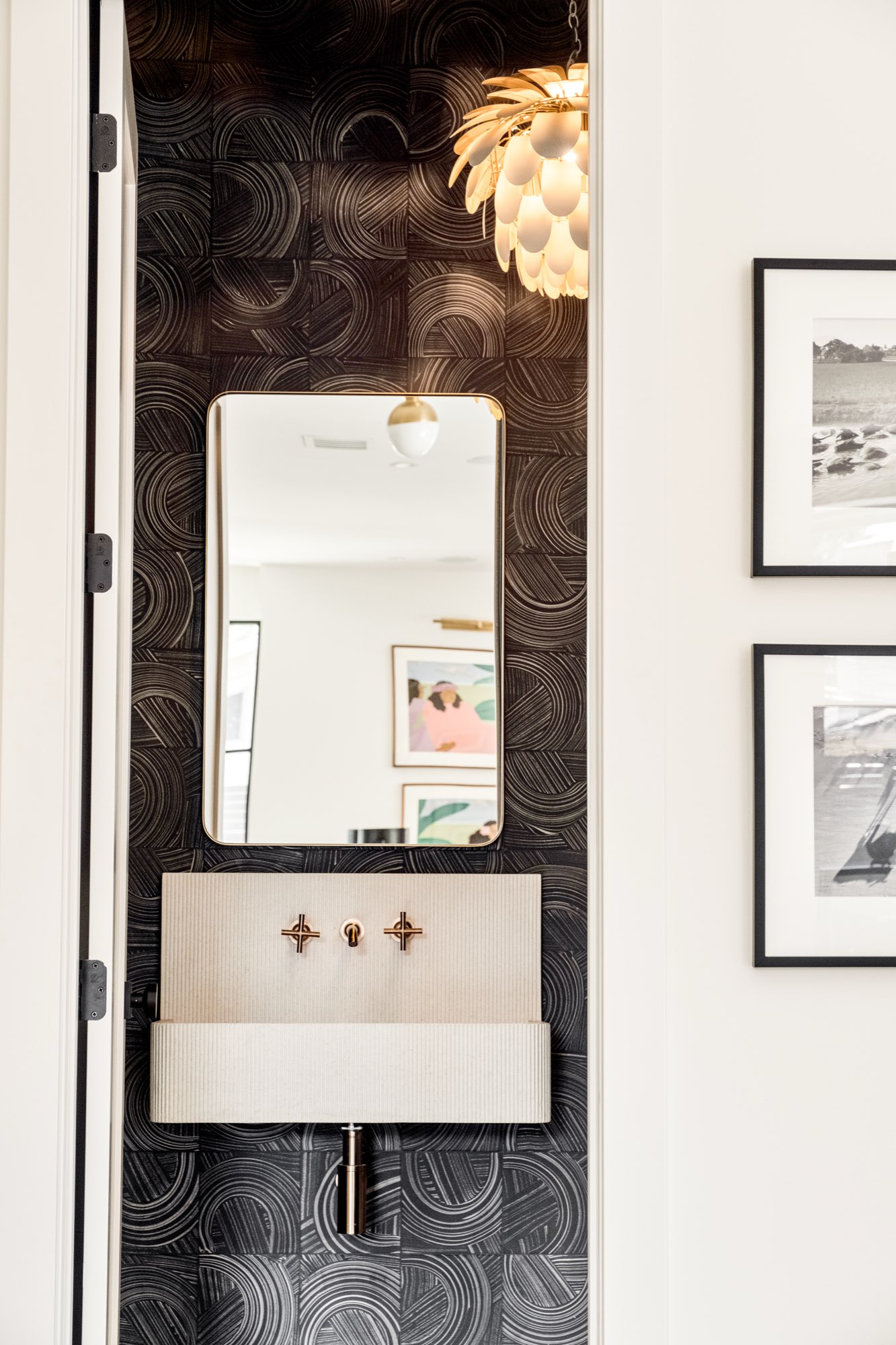 Powder room with dark patterned tile, a wall-mounted sink, a framed mirror and a pendant light