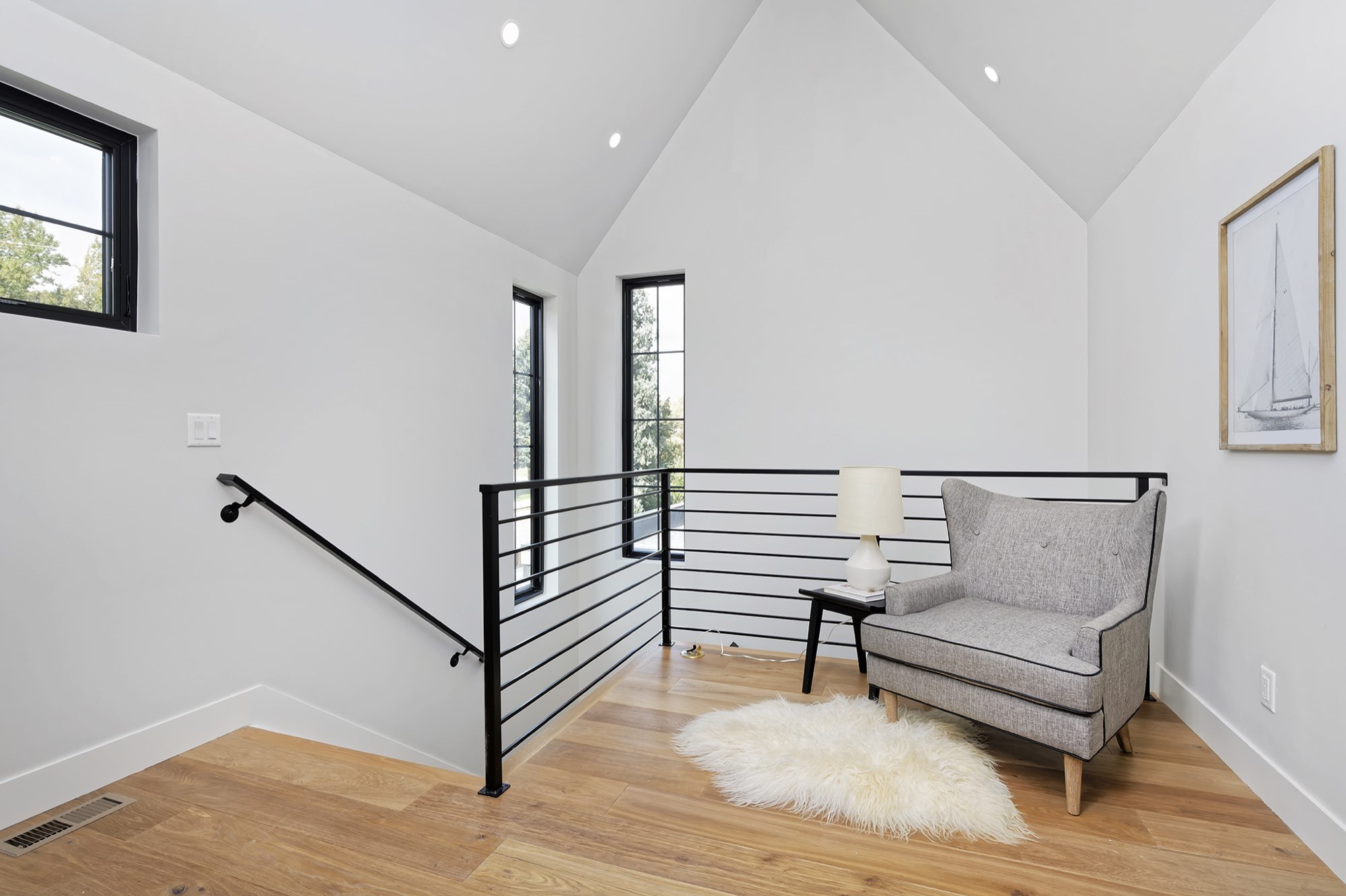 Upstairs landing with a black horizontal stair railing, wood floors and a vaulted ceiling