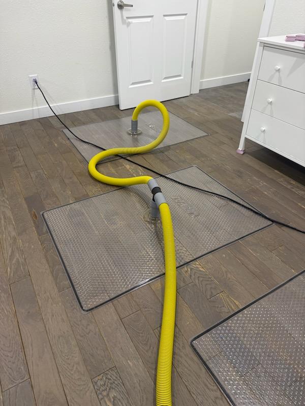 Drying mats pulling moisture out of a water-damaged hardwood floor