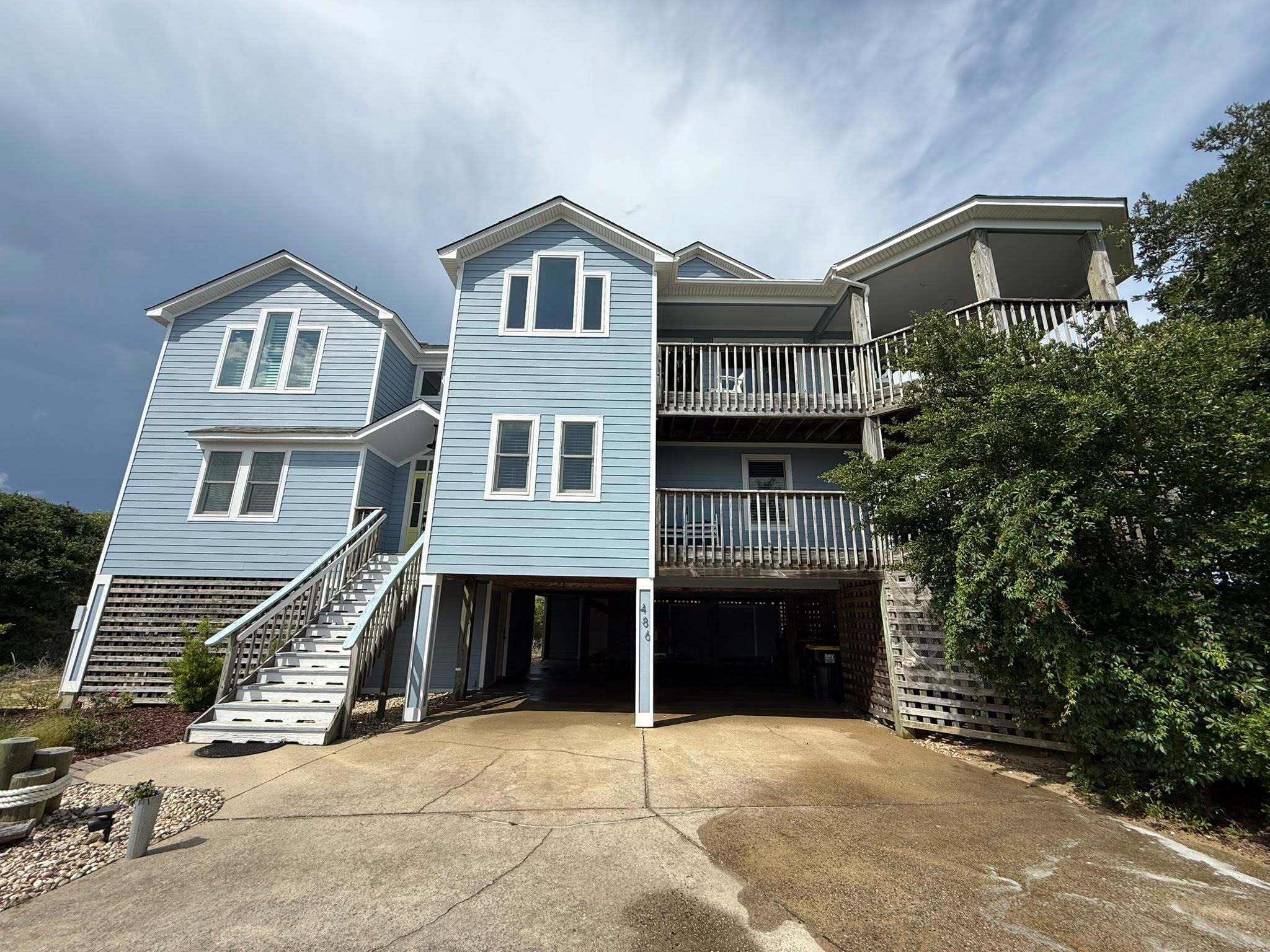 Blue raised beach house in Nags Head, NC with clean concrete driveway