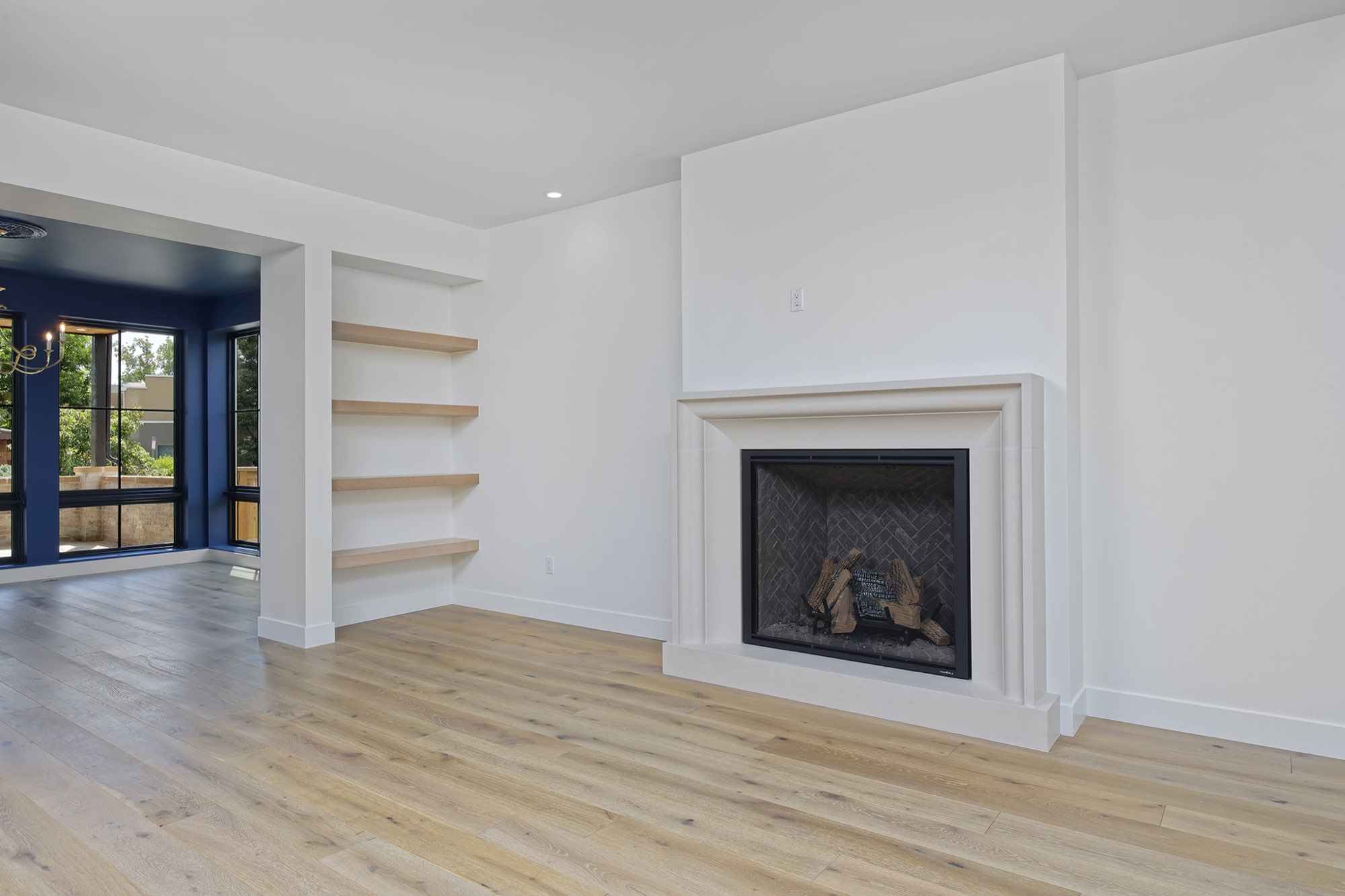 Fireplace with built-in floating wood shelves, with the blue dining room visible through the opening